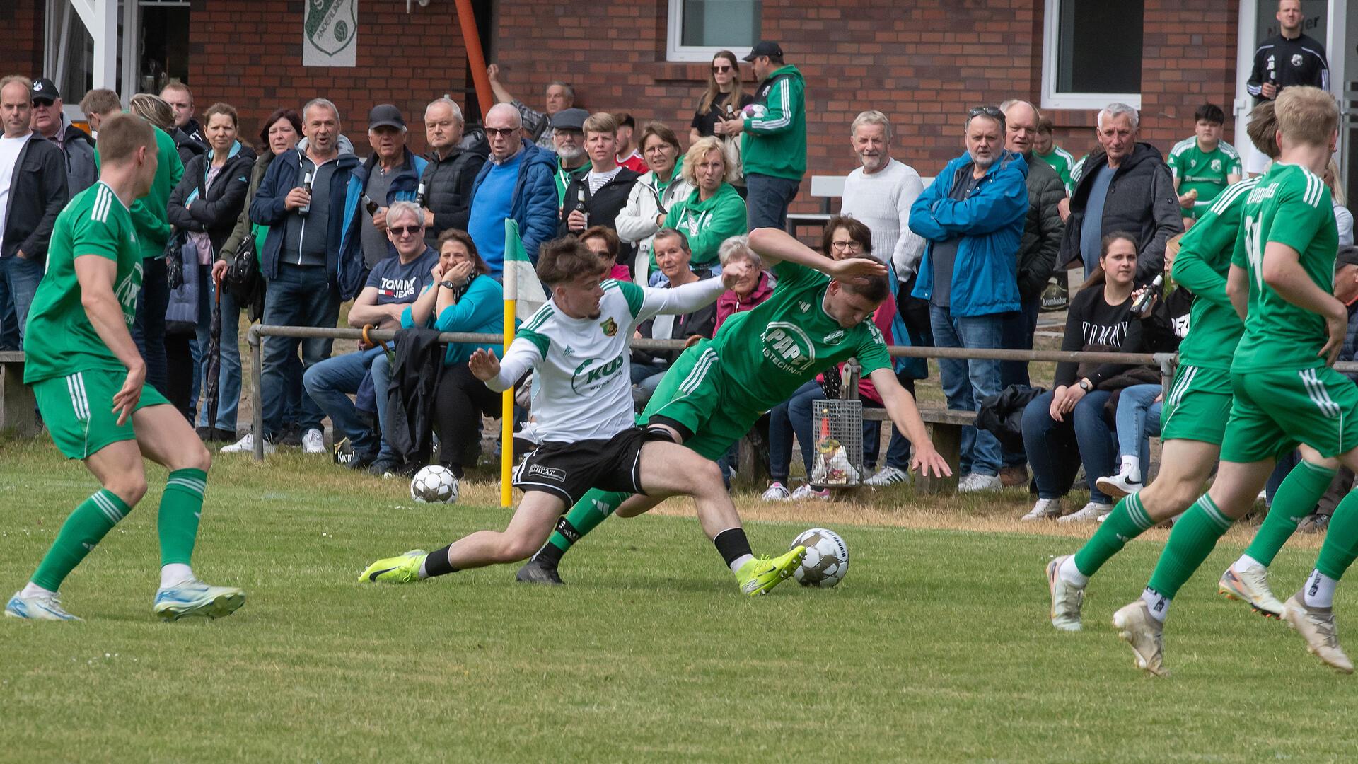 Zwei Männer kämpfen um einen Ball und viele Menschen schauen zu.