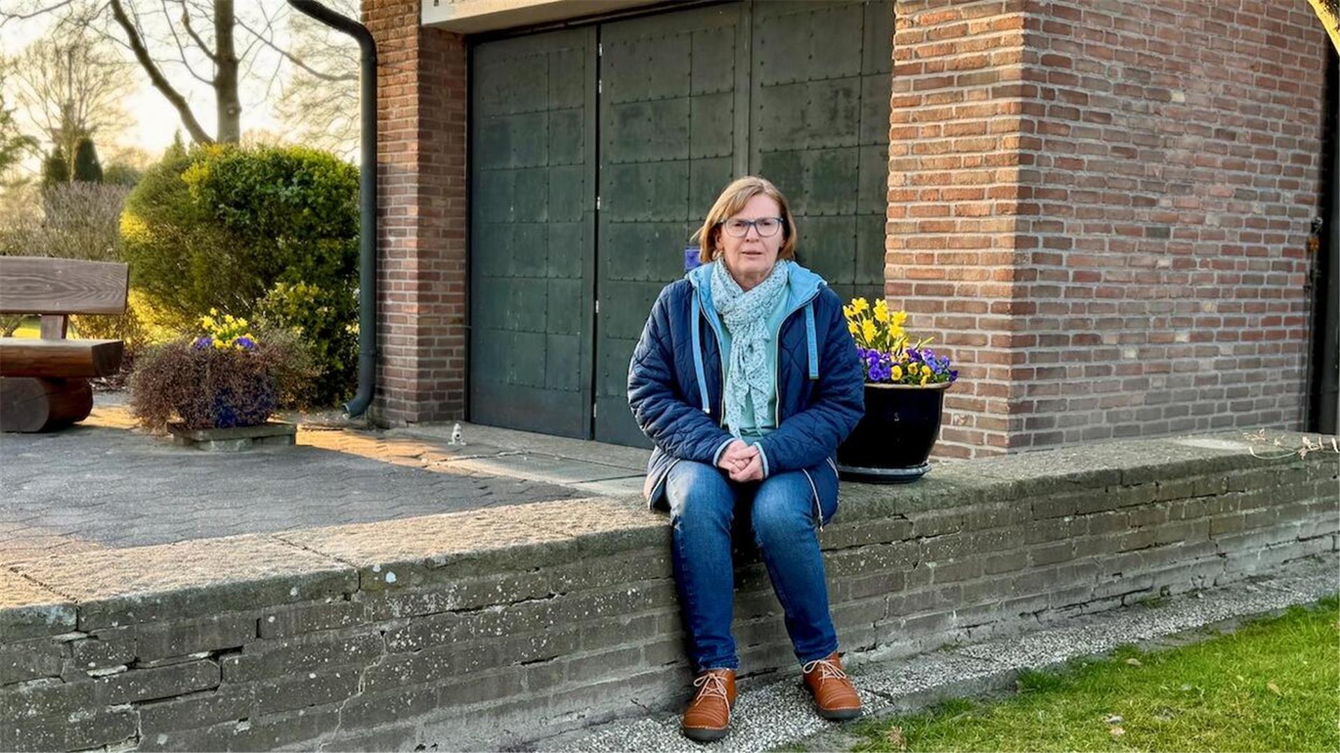 Eine Frau sitzt vor einer Kirche.