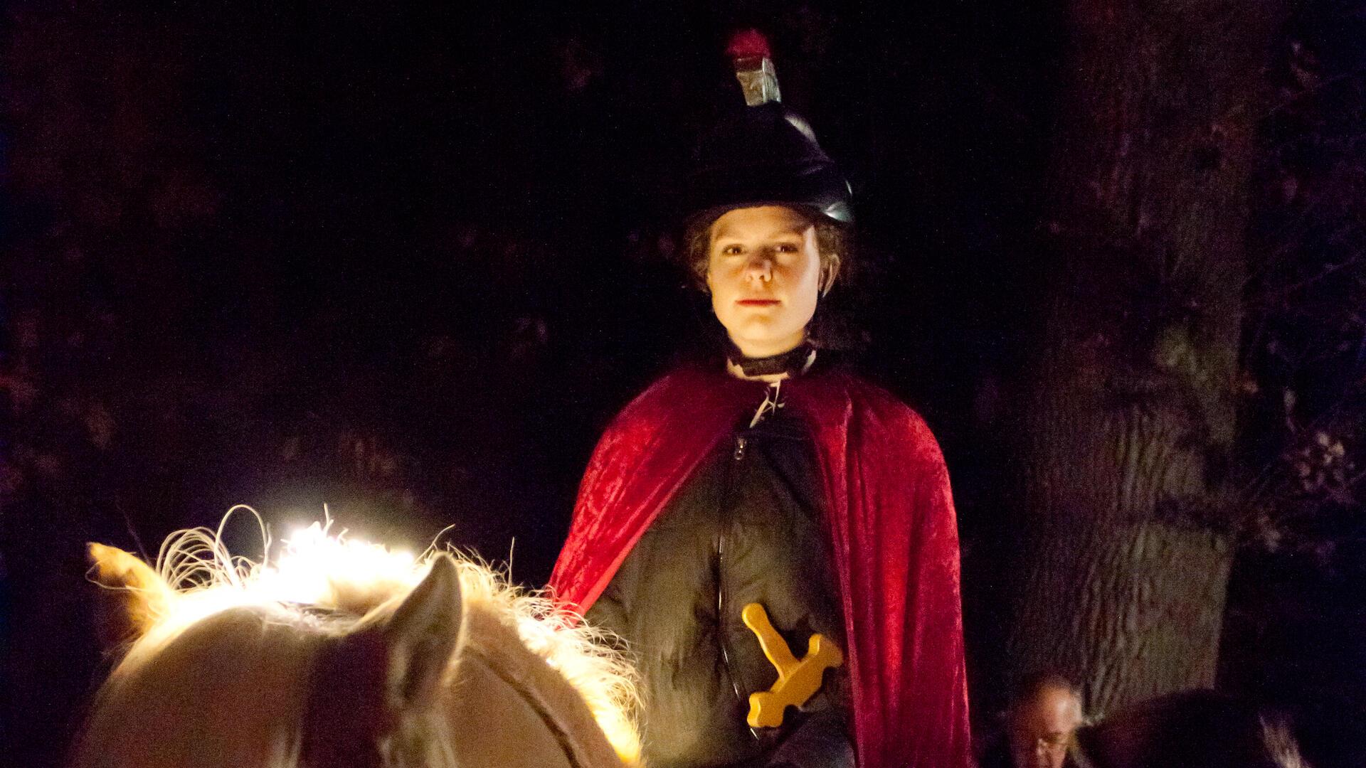 Frau in Mantel auf Pferd