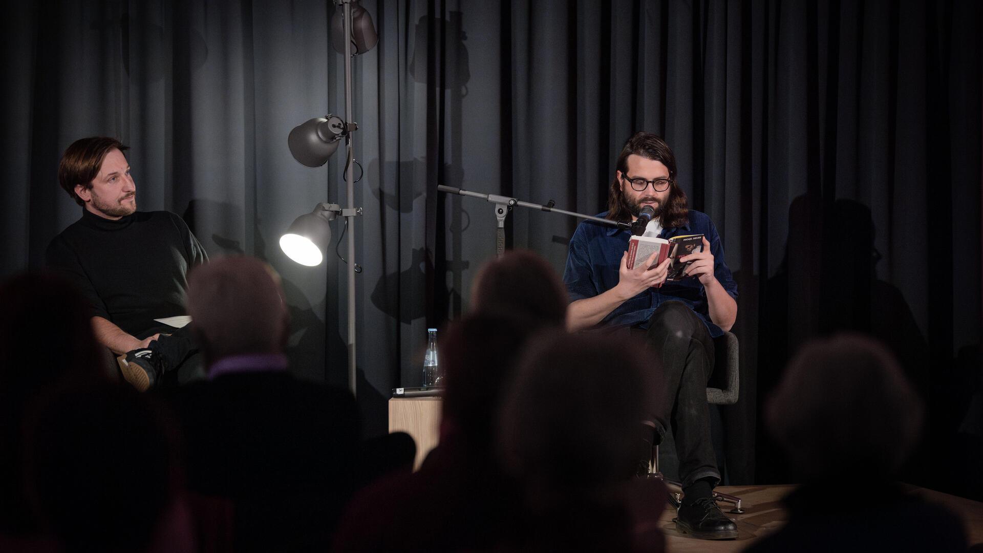 Michel Decar (rechts) stellt den Zuhörern am vierten Abend der Literarischen Wochen den Taugenichts vor, der in dem satirischen Künstlerroman „Kapitulation“ das Schreiben aufgeben will. Da hört nicht nur Tobias Pollok, der Kulturreferent der Arbeitnehmerkammer, aufmerksam zu.
