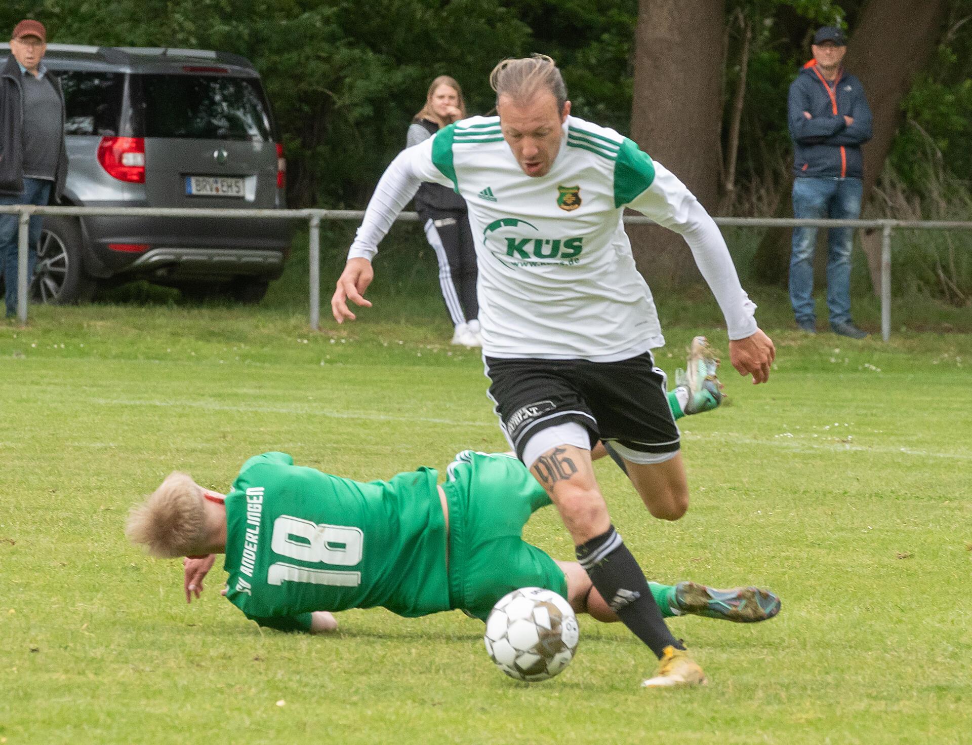 Ein Mann läuft mit einem Ball am Fuß an einem anderen Mann vorbei.