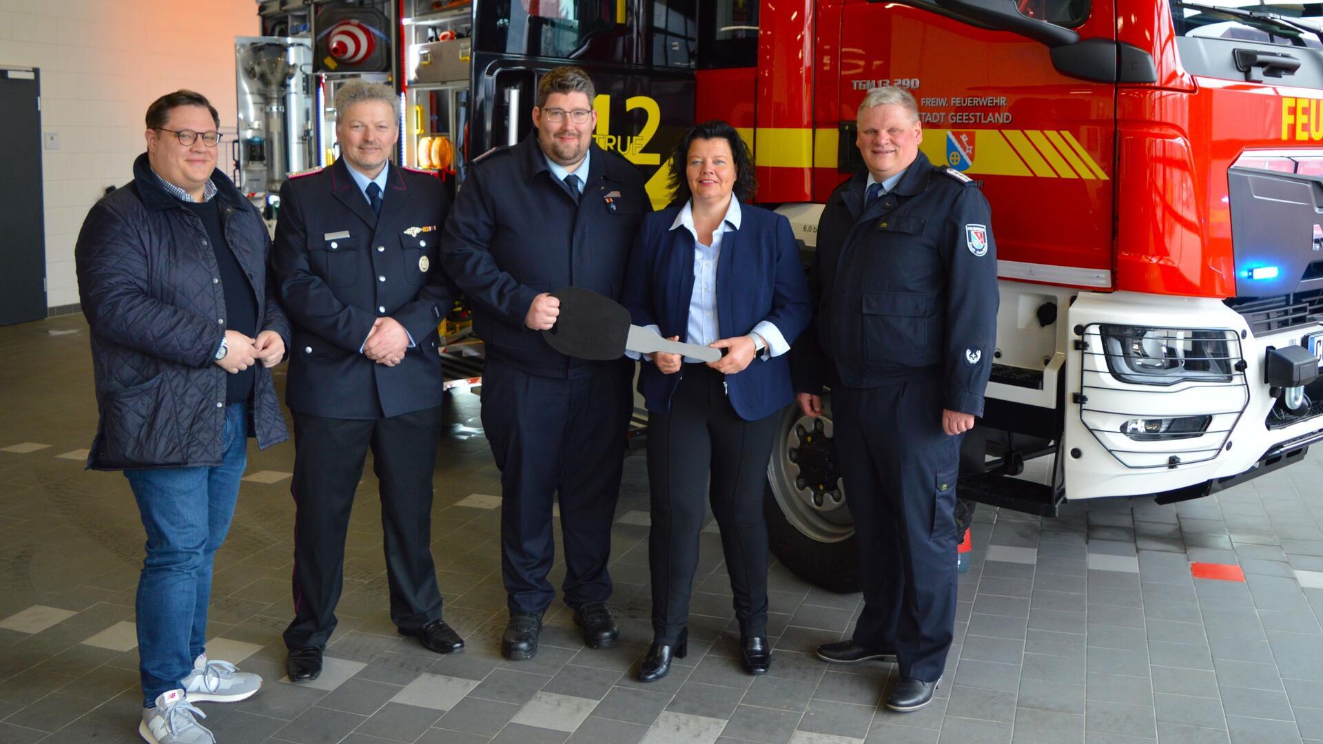 Eine Personengruppe steht vor einem neuen Tanklöschfahrzeug. Die Stadt Geestland hat ein neues Tanklöschfahrzeug an die Feuerwehr Langen übergeben.