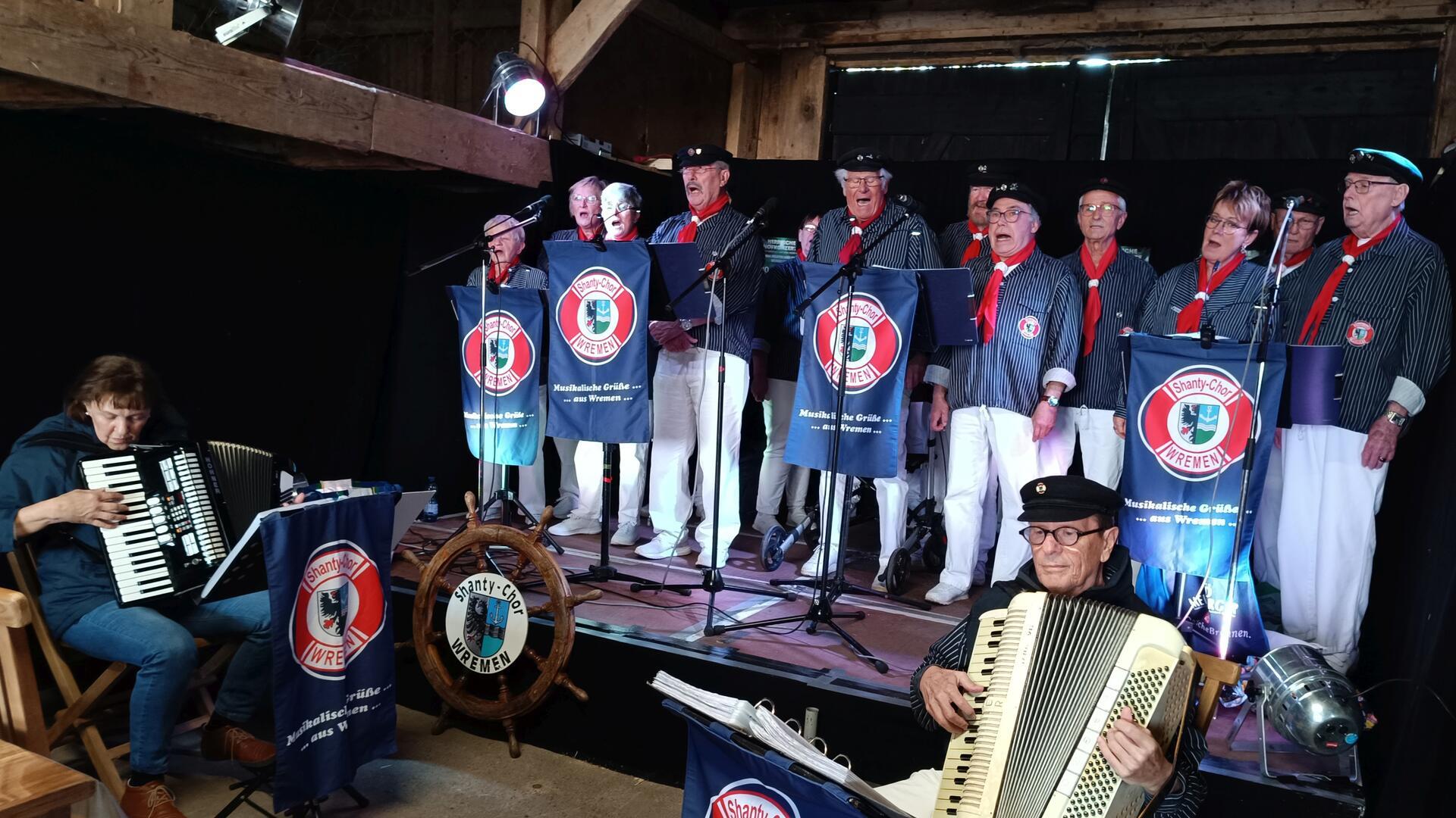 Mitglieder des Shanty-Chors Wremen stehen hinter Mikrofonen. 
