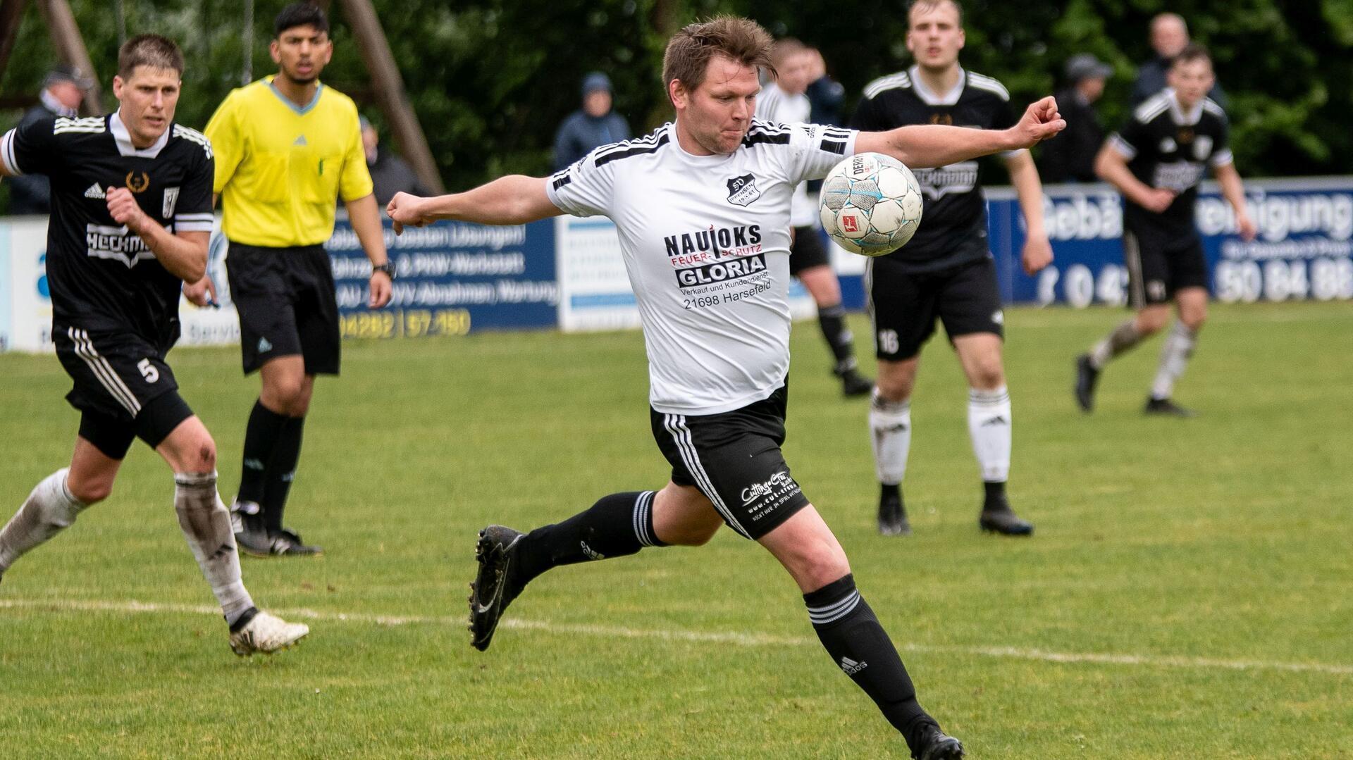 Ein Mann in einem schwarz-weißen Trikot schießt einen Ball.