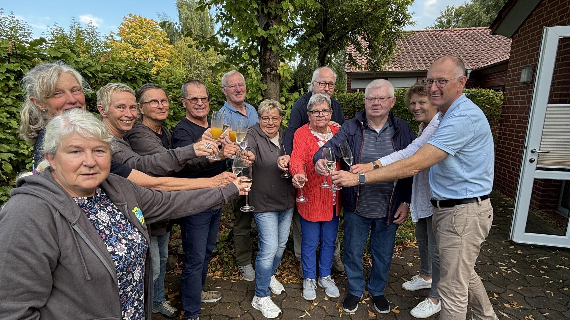 Mitglieder der Fairtrade-Steuerungsgruppe Loxstedt stoßen im Freien mit Sektgläsern auf das einjährige Bestehen der Fairtrade-Gemeinde an.