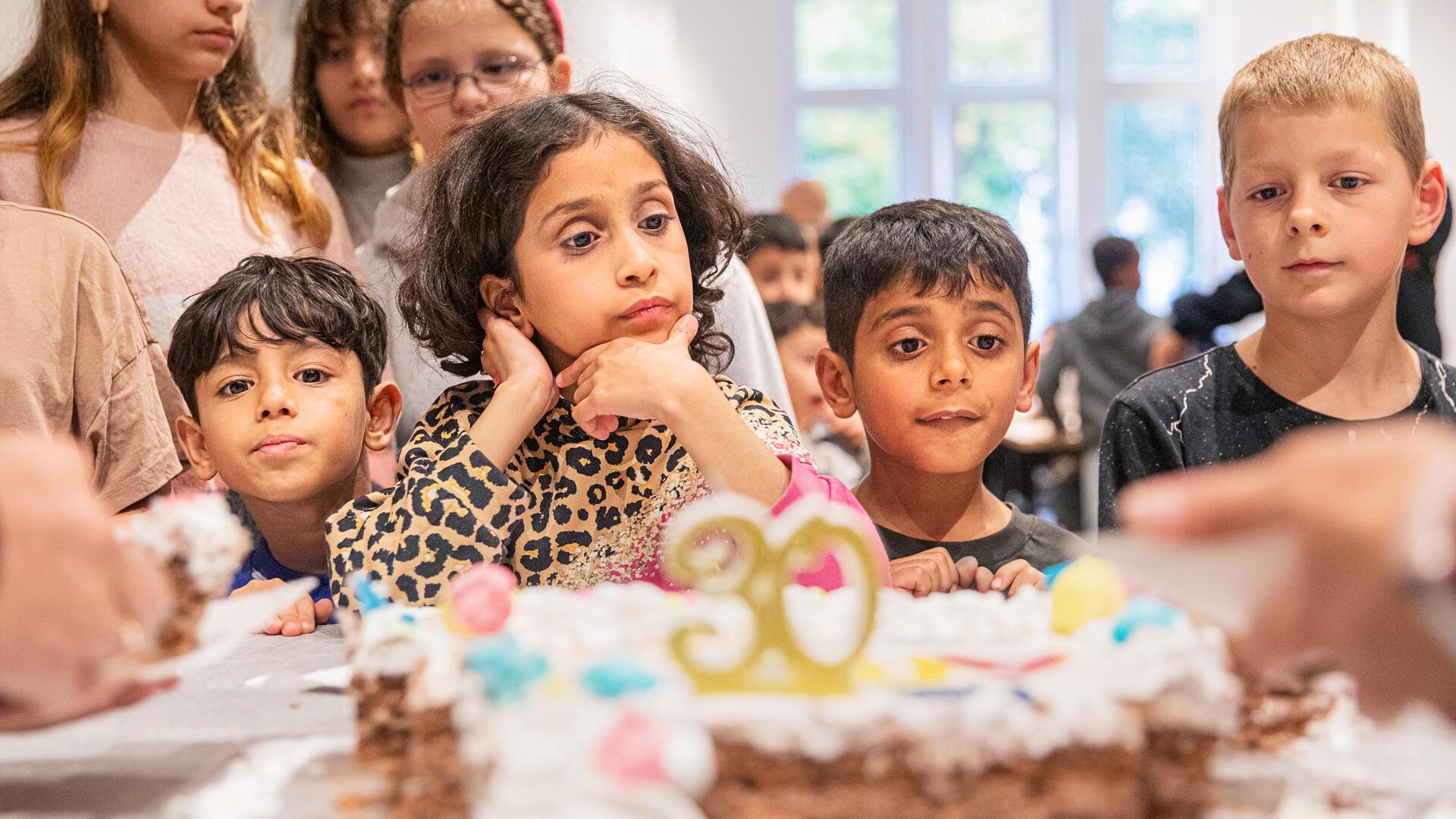 Kinder stehen vor einer Torte.