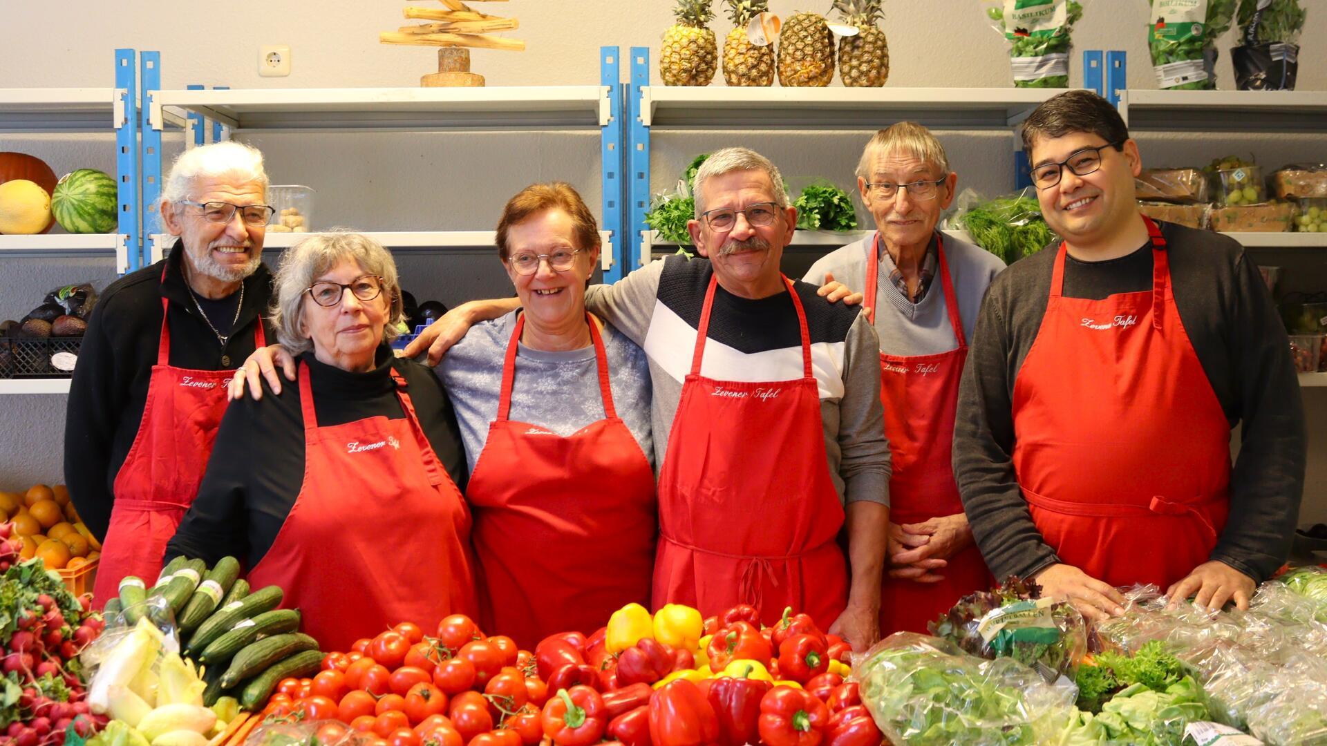 Sechs Menschen mit roten Schürzen