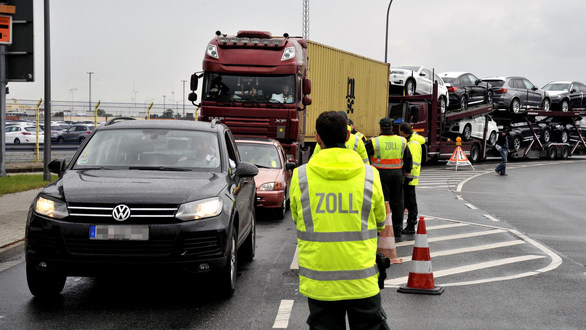 Zollbeamte vor Autokolonne.