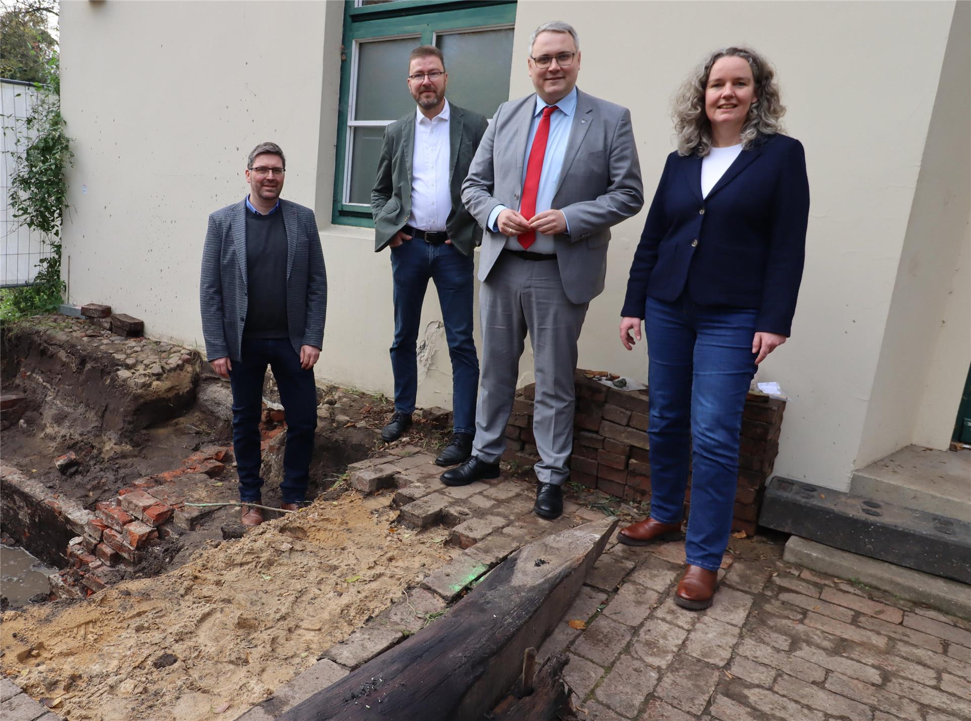 Museumsleiterin Ellen Horstrup (von rechts), Landrat Marco Prietz, Kreisarchäologe Dr. Stefan Hesse und Projektleiter Landkreis Eike Burfeind vor einer Grabung im Außenbereich des Museums. 