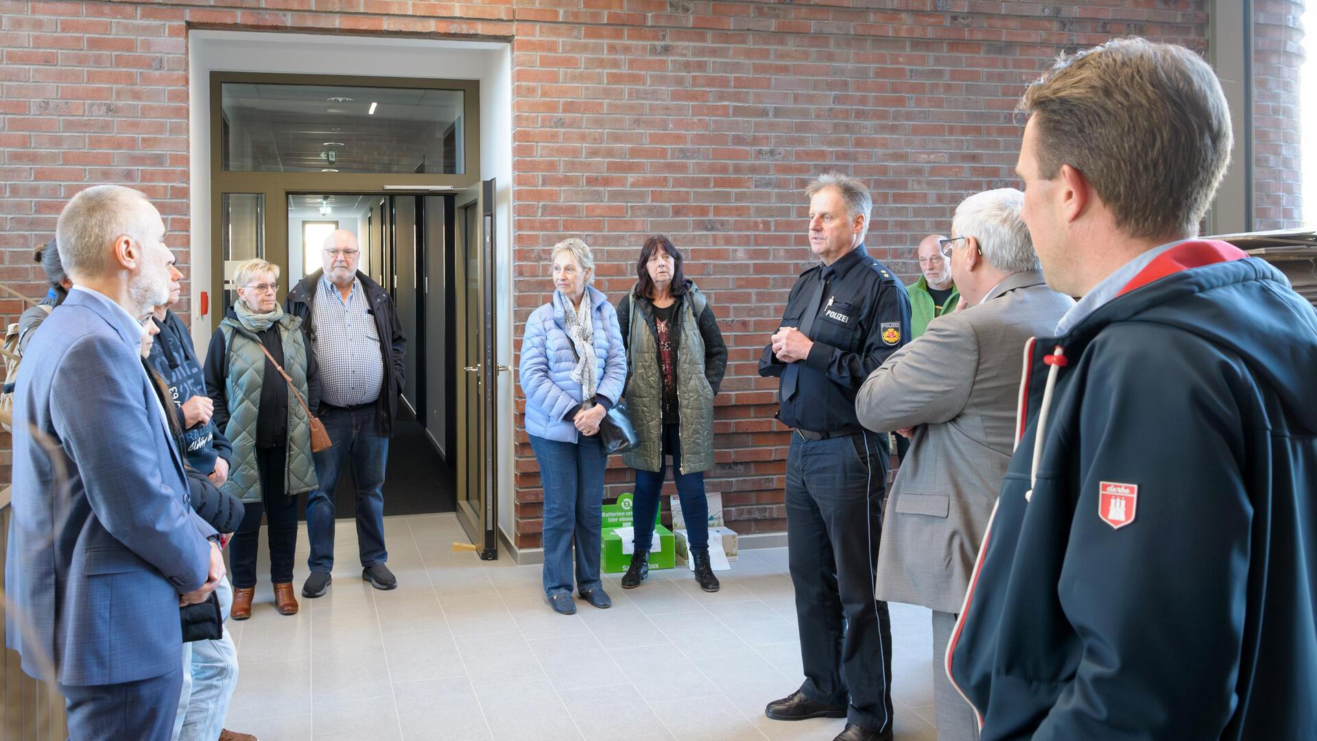 Sechs Männer und fünf Frauen stehen vor einem Polizeirevier und lächeln in die Kamera.