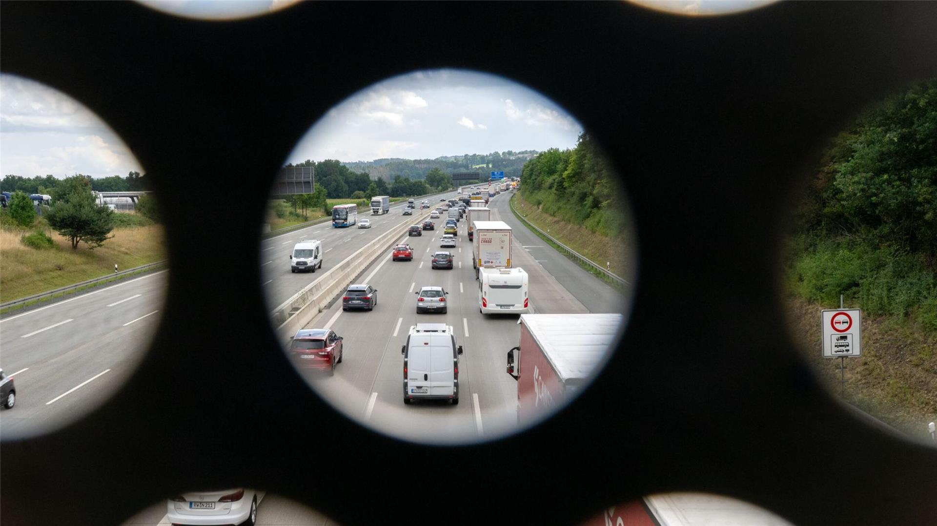  Zahlreiche Autos stehen auf der Autobahn im Stau, Aufnahme durch das Geländer einer Brücke