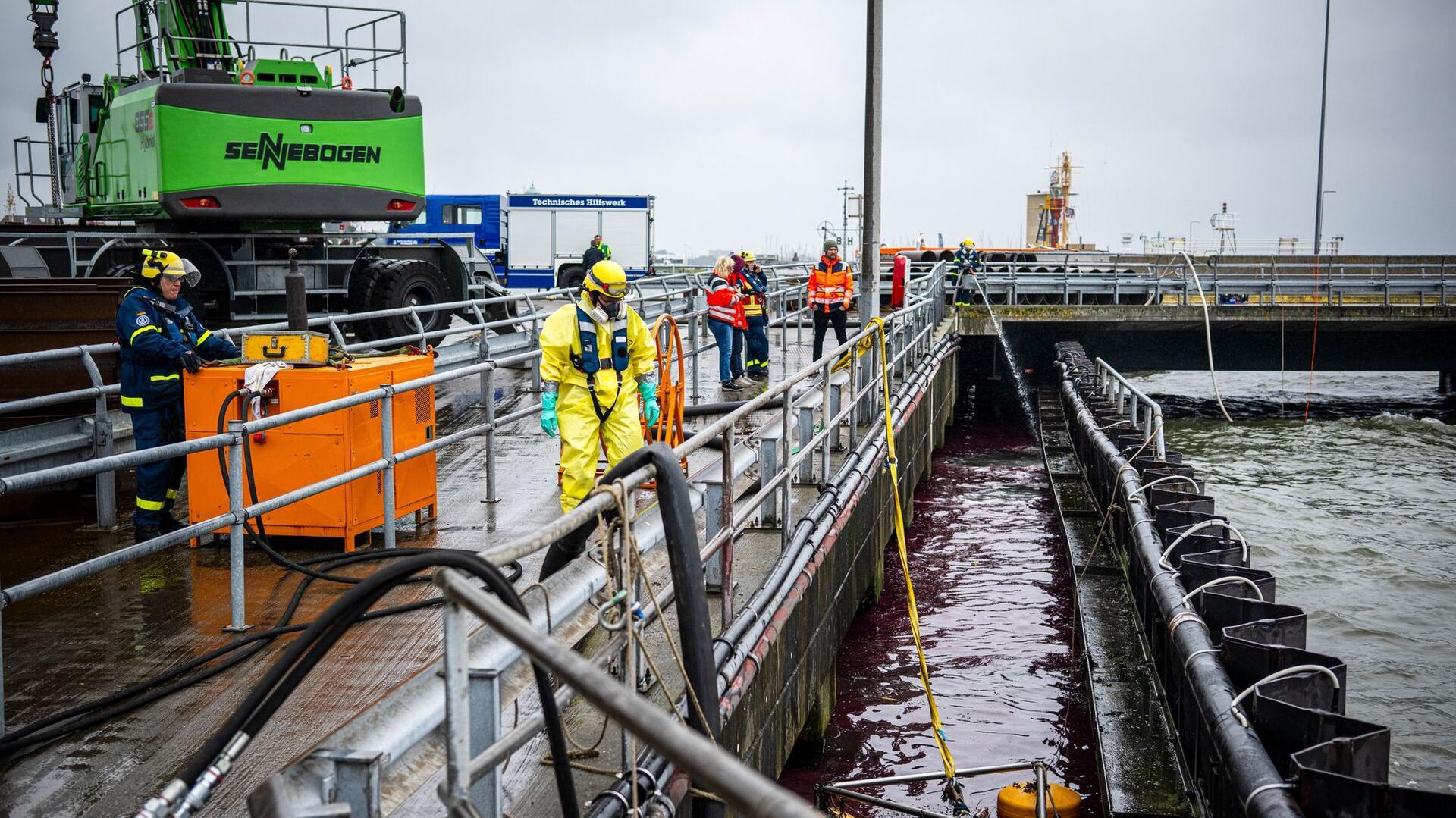 Mit Spezialausrüstung bekämpfen Einsatzkräfte das ausgelaufene Öl im Hafen.