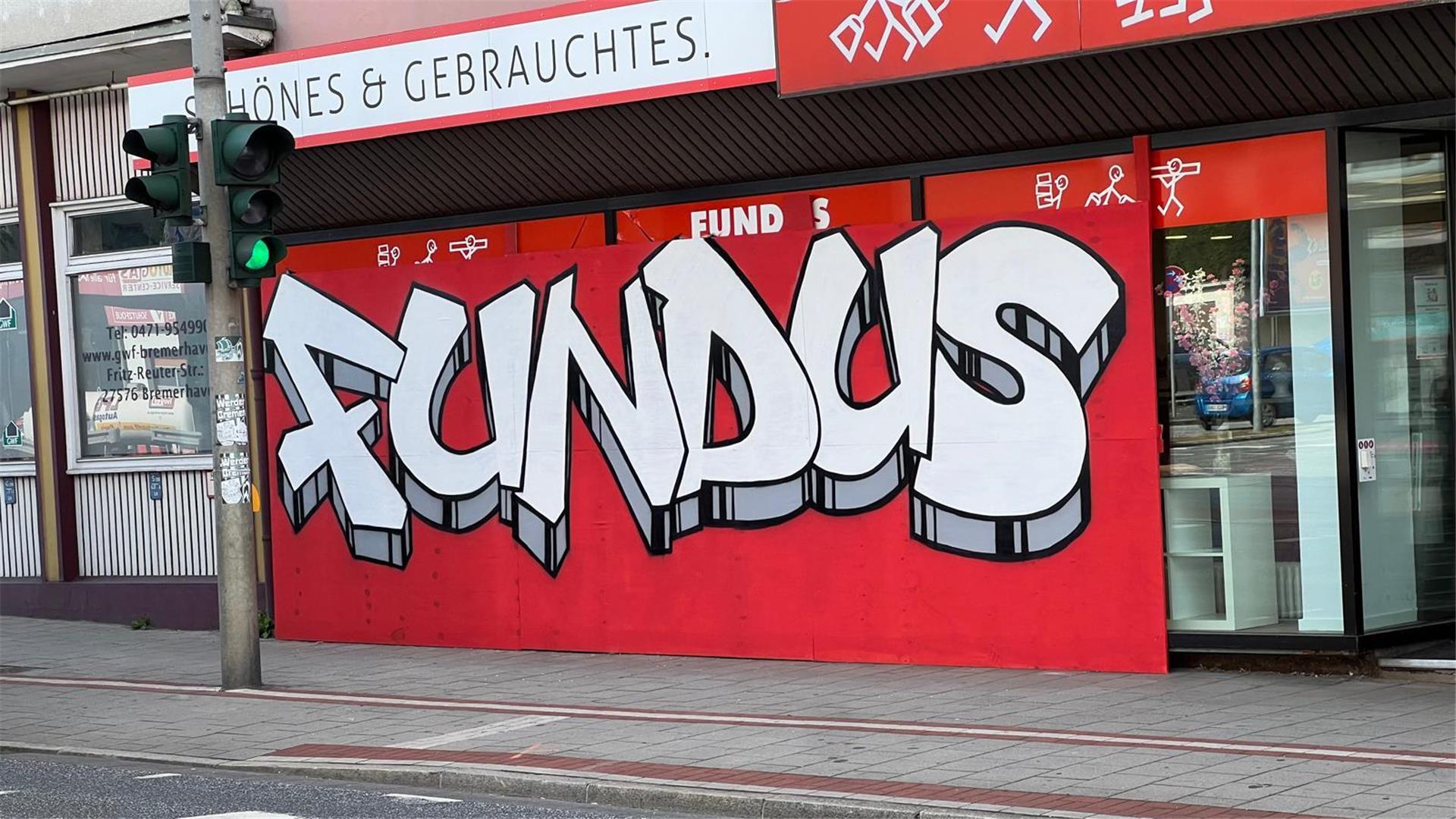 Nach einem Unfall ist das Schaufenster des Fundus mit Sperrholz verkleidet. Eine Graffiti-Aktion macht daraus einen farbenfrohen Blickfang.
