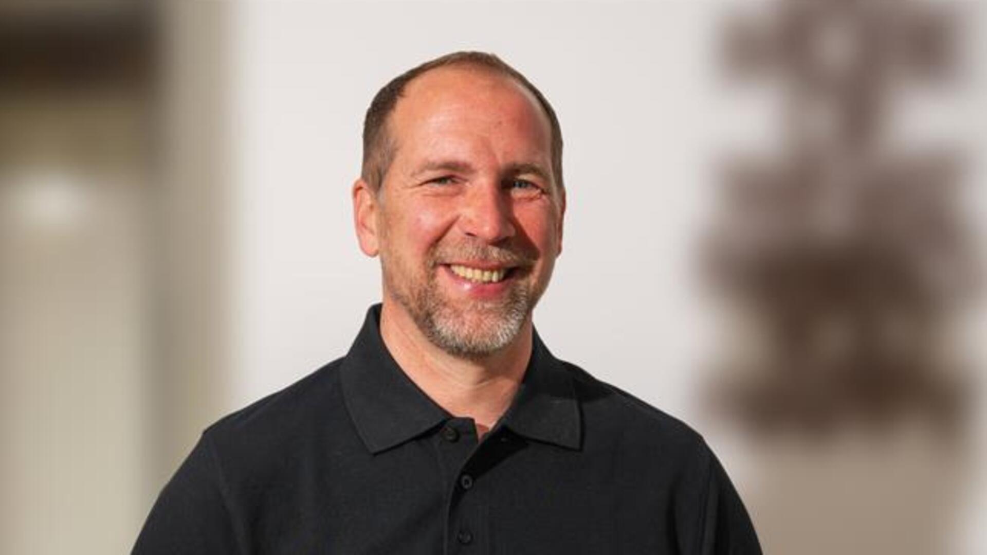 Ein Mann mit einem schwarzen Poloshirt lächelt in die Kamera. Nach einer zehnmonatigen Auszeit ist Steffen Heumann bereit für eine neue berufliche Herausforderung.