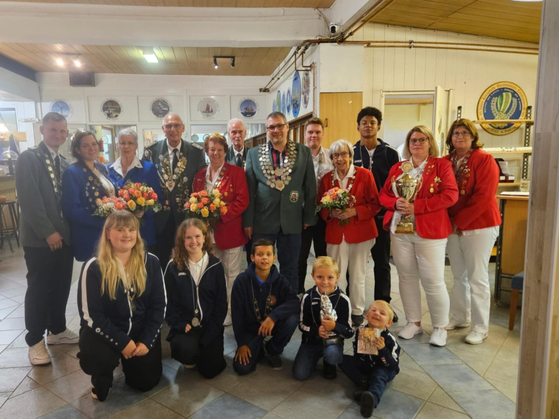 Große Schützenfamilie mit Blumensträußen und Schützenketten an Uniformjacken