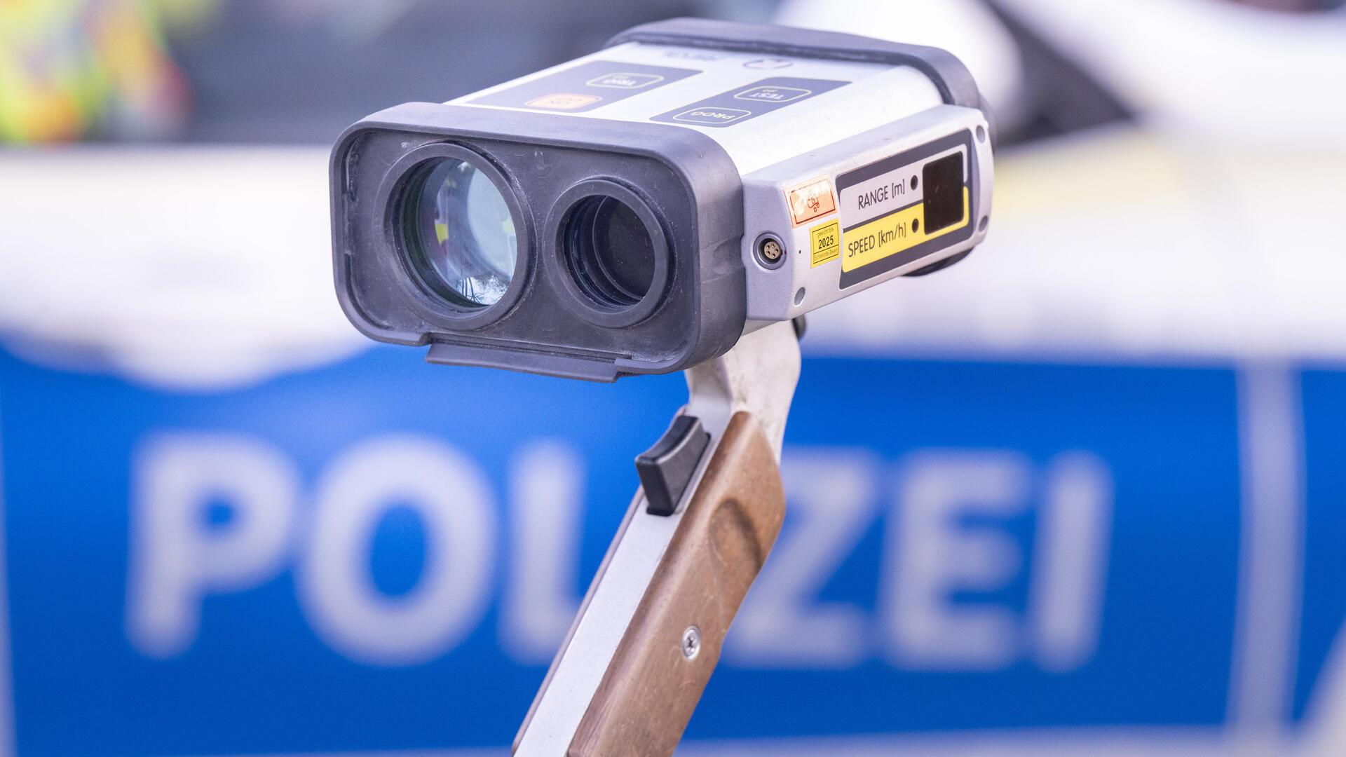 Ein Geschwindigkeitsmesser steht vor einem Polizeiwagen. 