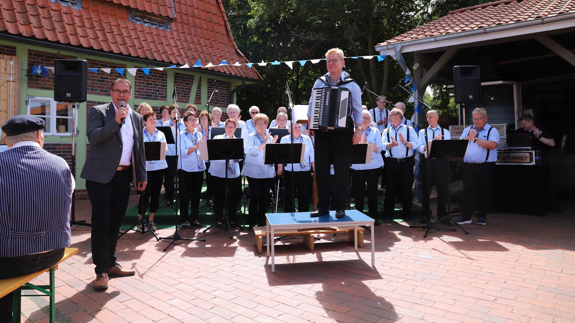 Nieder Ochtenhausens Bürgermeister Stefan Imbusch (links) gratulierte der Singgruppe des Heimatvereins Nieder Ochtenhausen zu ihrem 40-jährigen Bestehen, das am Sonntag mit einem „Bunten Musikfest“ am historischen Kornspeicher gefeiert wurde.