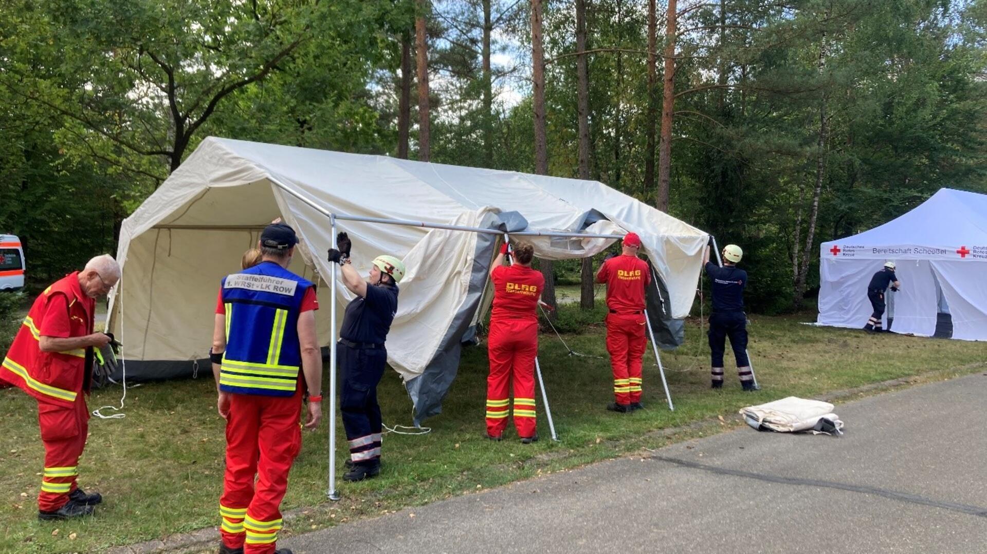 Ob rote oder blaue Uniform - die Zusammenarbeit beim Aufbau der Zelte für die medizinische Versorgung läuft reibungslos.