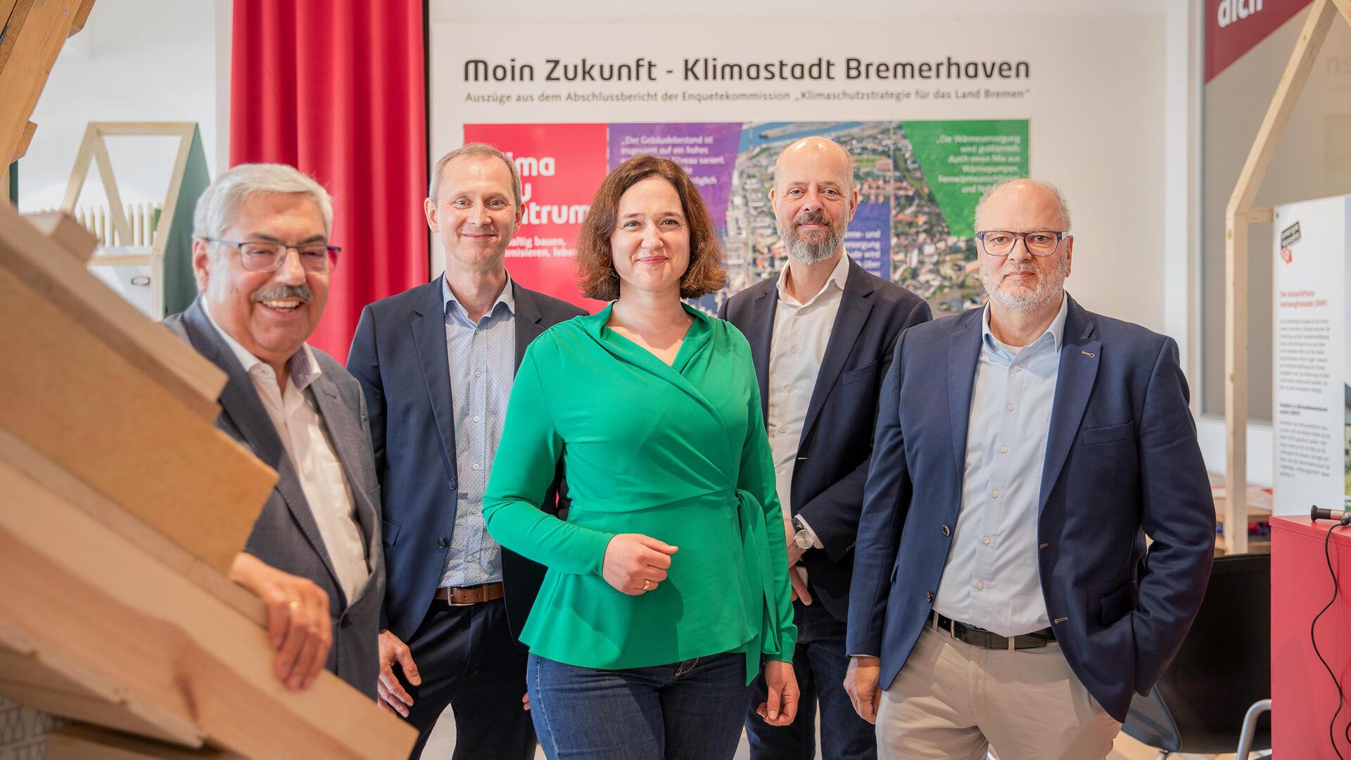 Fünf Personen stehen in der neuen Beratungsstelle - vier Männer und eine Frau in der Mitte. Alle lächeln in die Kamera. 