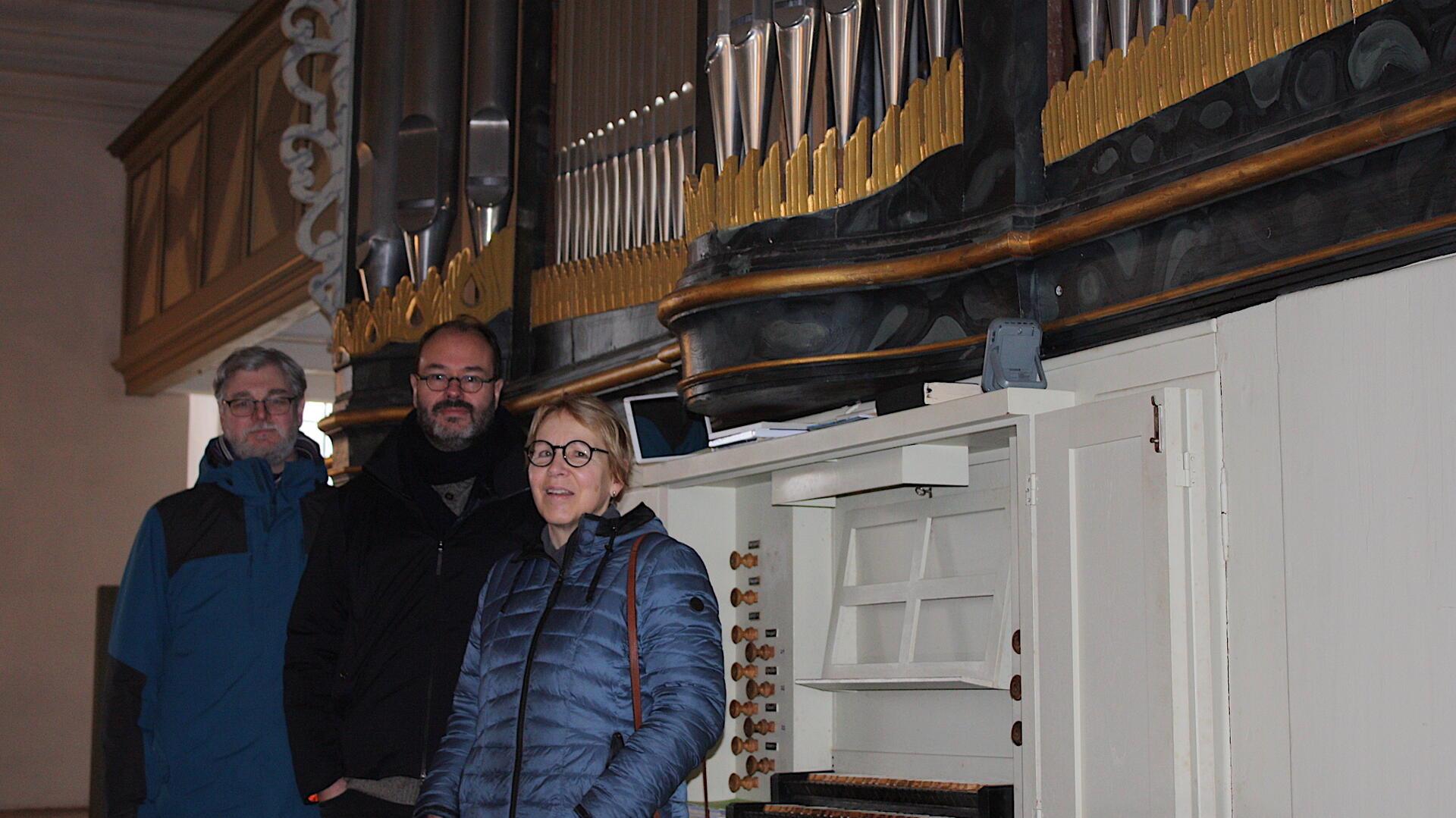 Drei Menschen stehen vor der Orgel der Bramstedter Kirche
