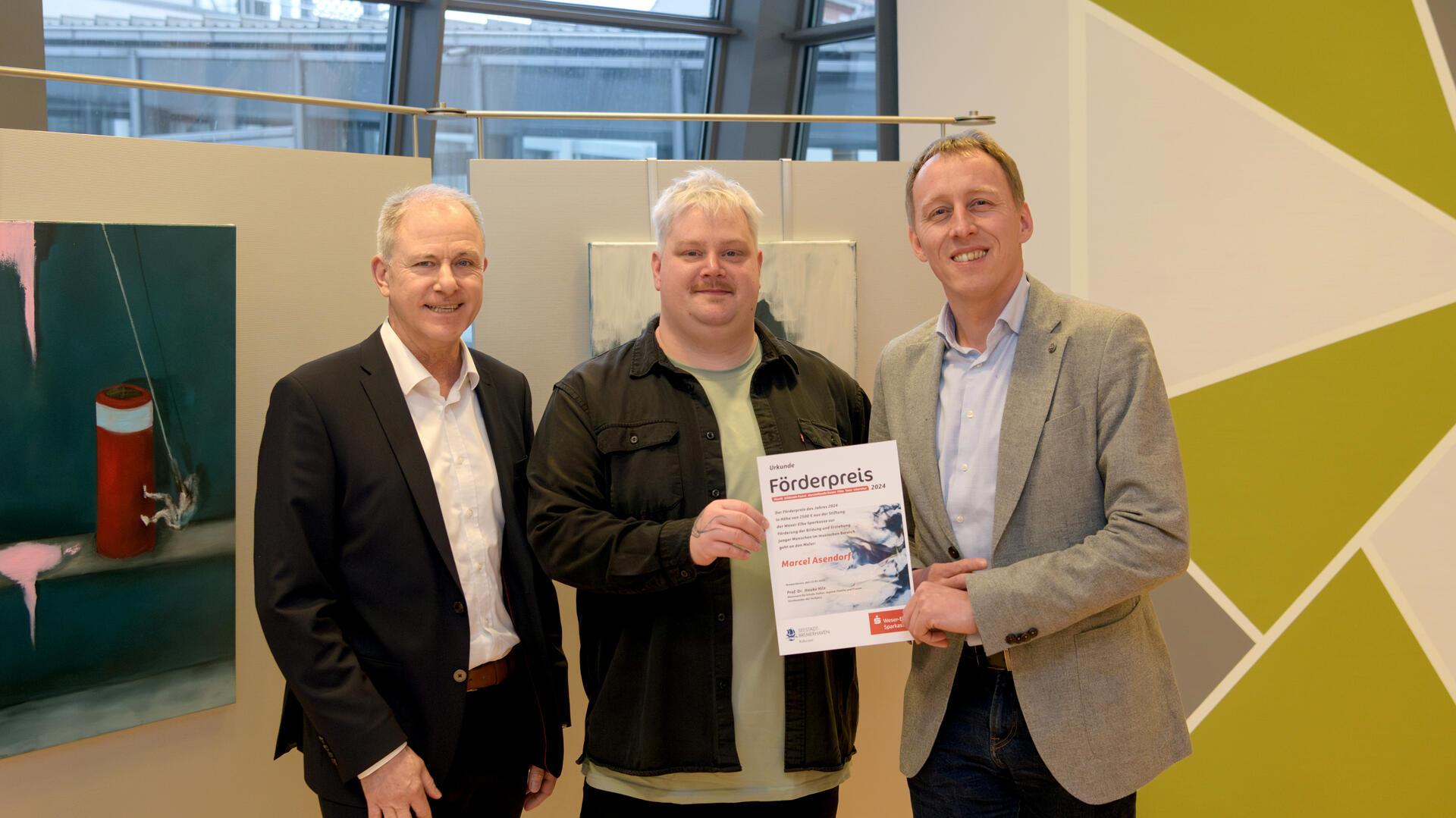 Drei Männer, der in der Mitte hält eine Urkunde in der Hand. WESPA-Vorstandsmitglied Alexander zu Putlitz, Preisträger Marcel Asendorf und Kulturstadtrat Hauke Hilz bei der Vergabe des Förderpreises der Stiftung der Weser-Elbe Sparkasse.