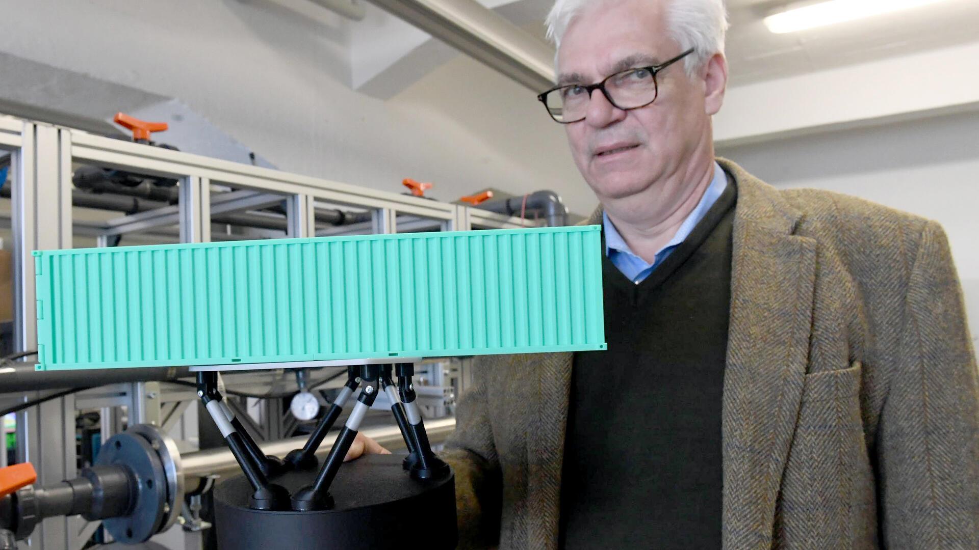 Professor Gerhard Schories vom ttz Bremerhaven zeigt ein Modell des Seegangssimulators.