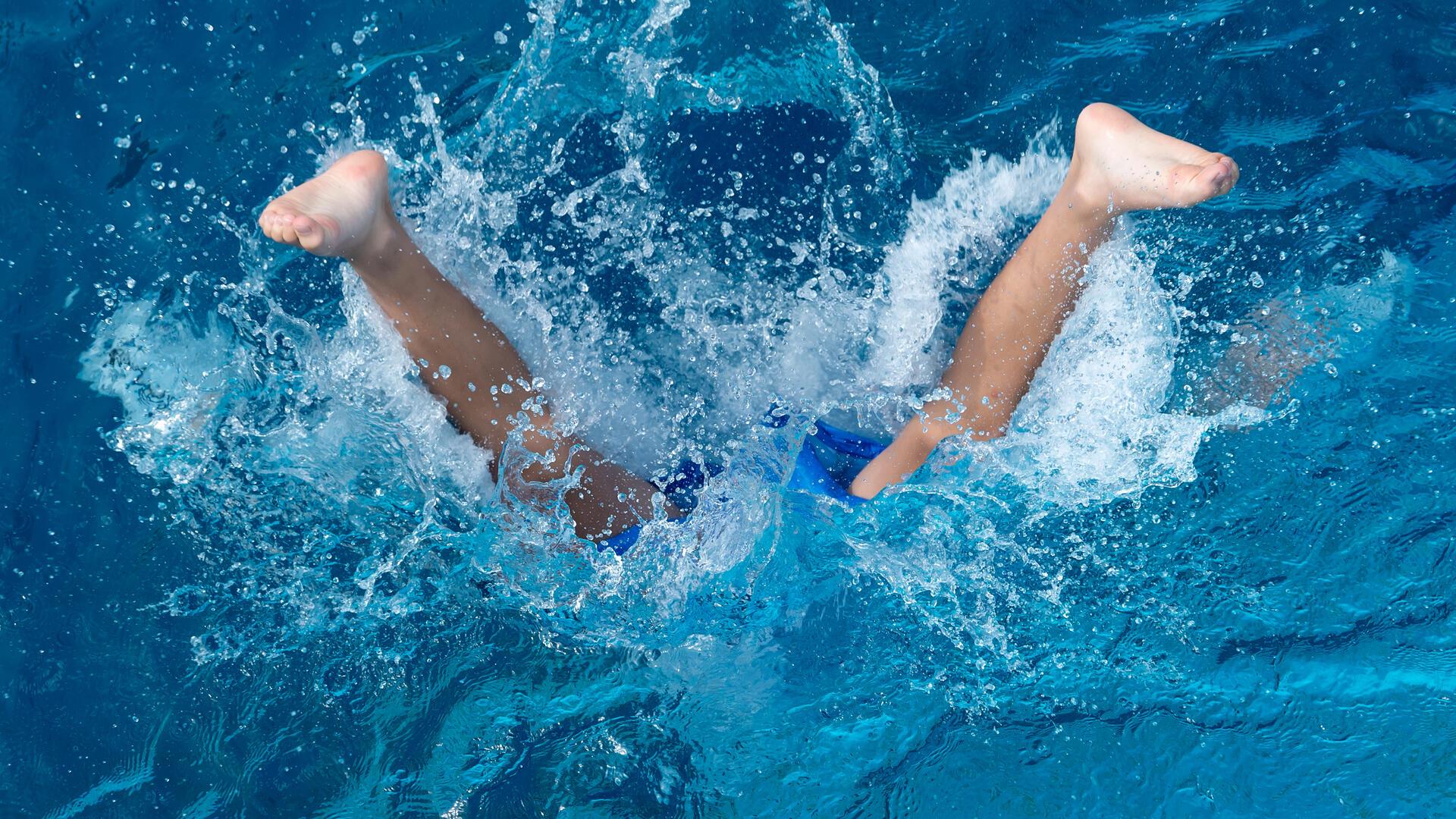Ein Junge springt in ein Schwimmbad.