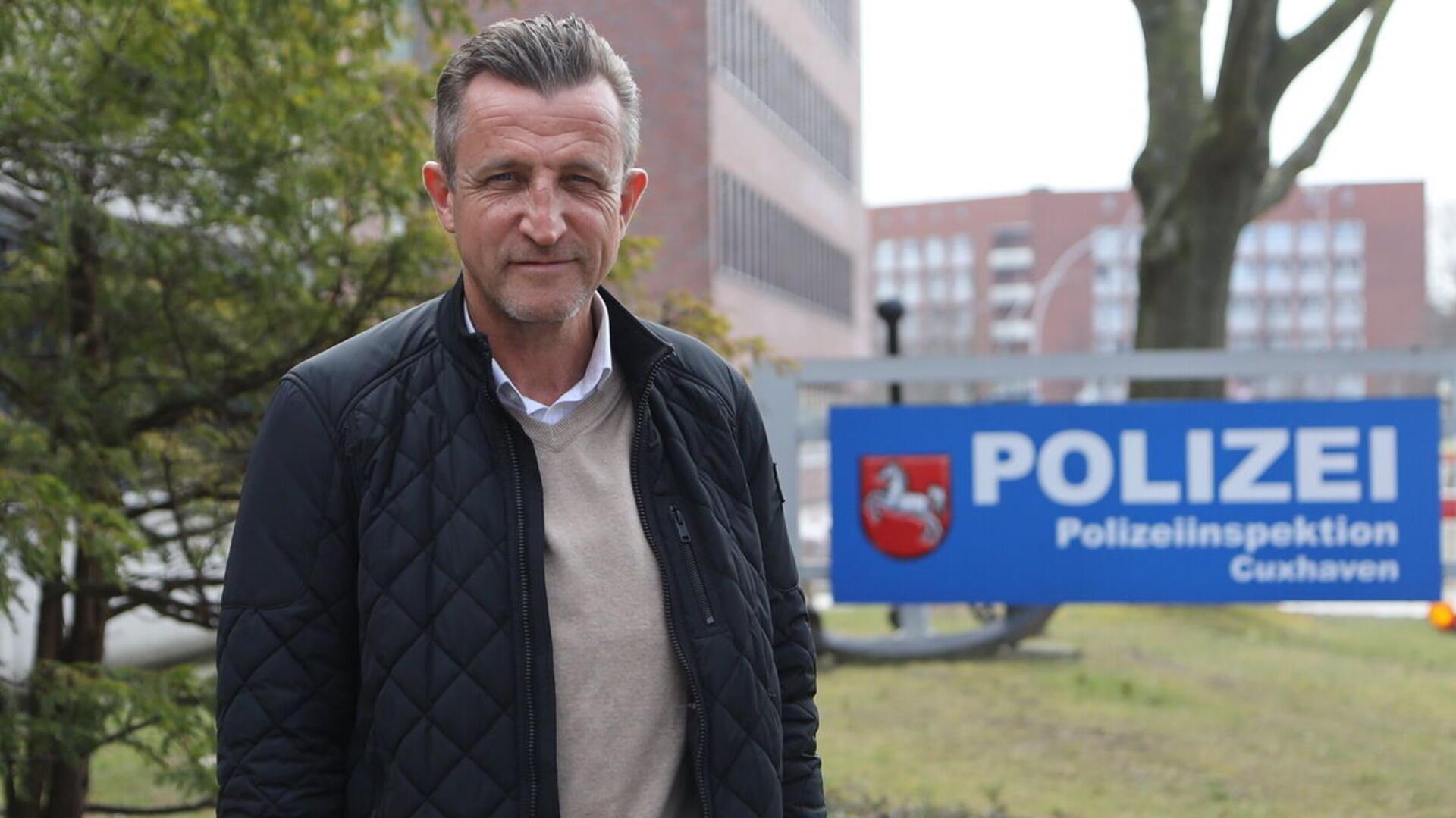 Rainer Brenner steht vor der Polizeiinspektion und blickt in Richtung der Kamera. 