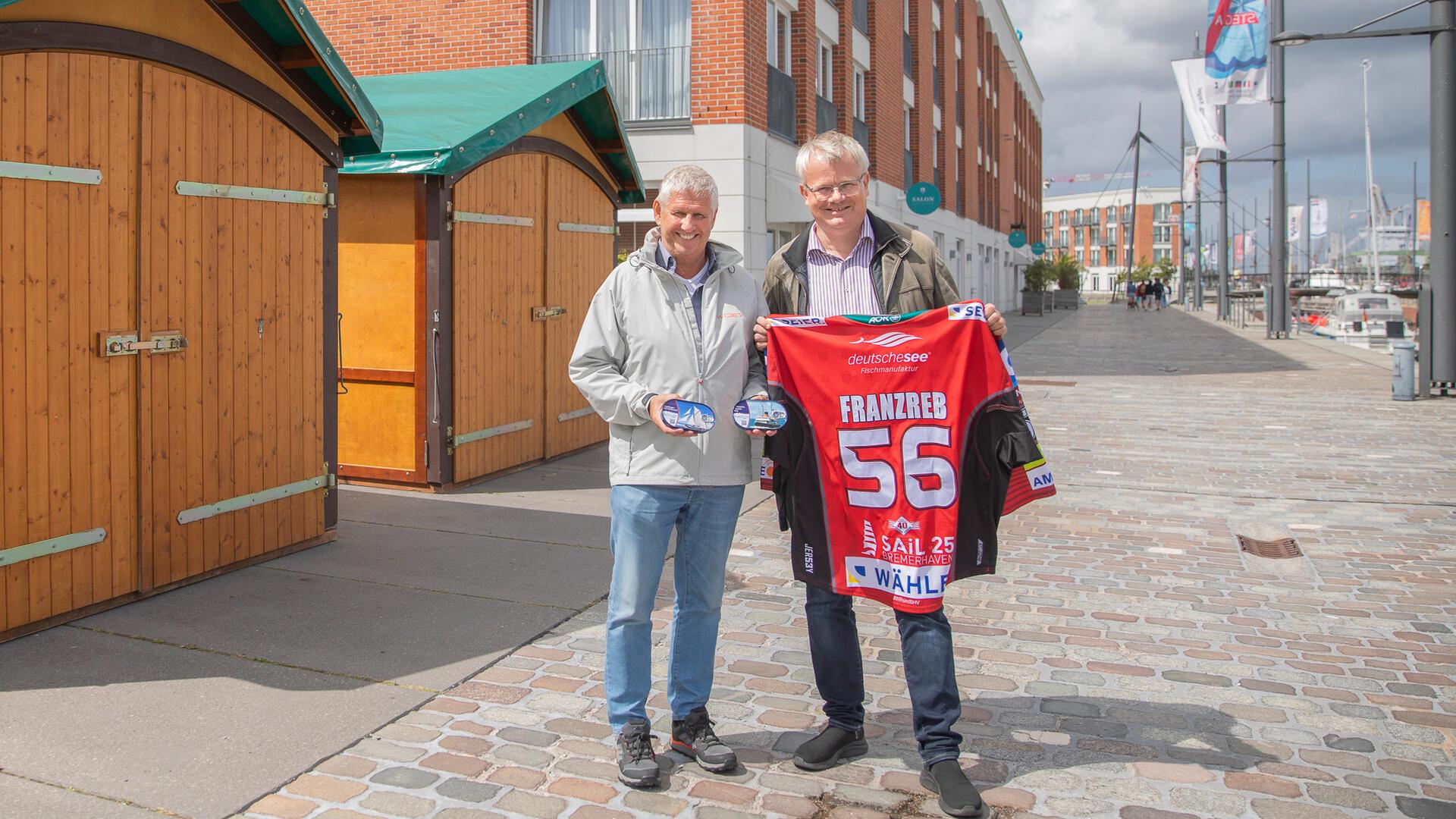 Rüdiger Pallentin (links) und Peter Klett zeigen, was Spender für Traditionsschiffe während der Sail gewinnen können.