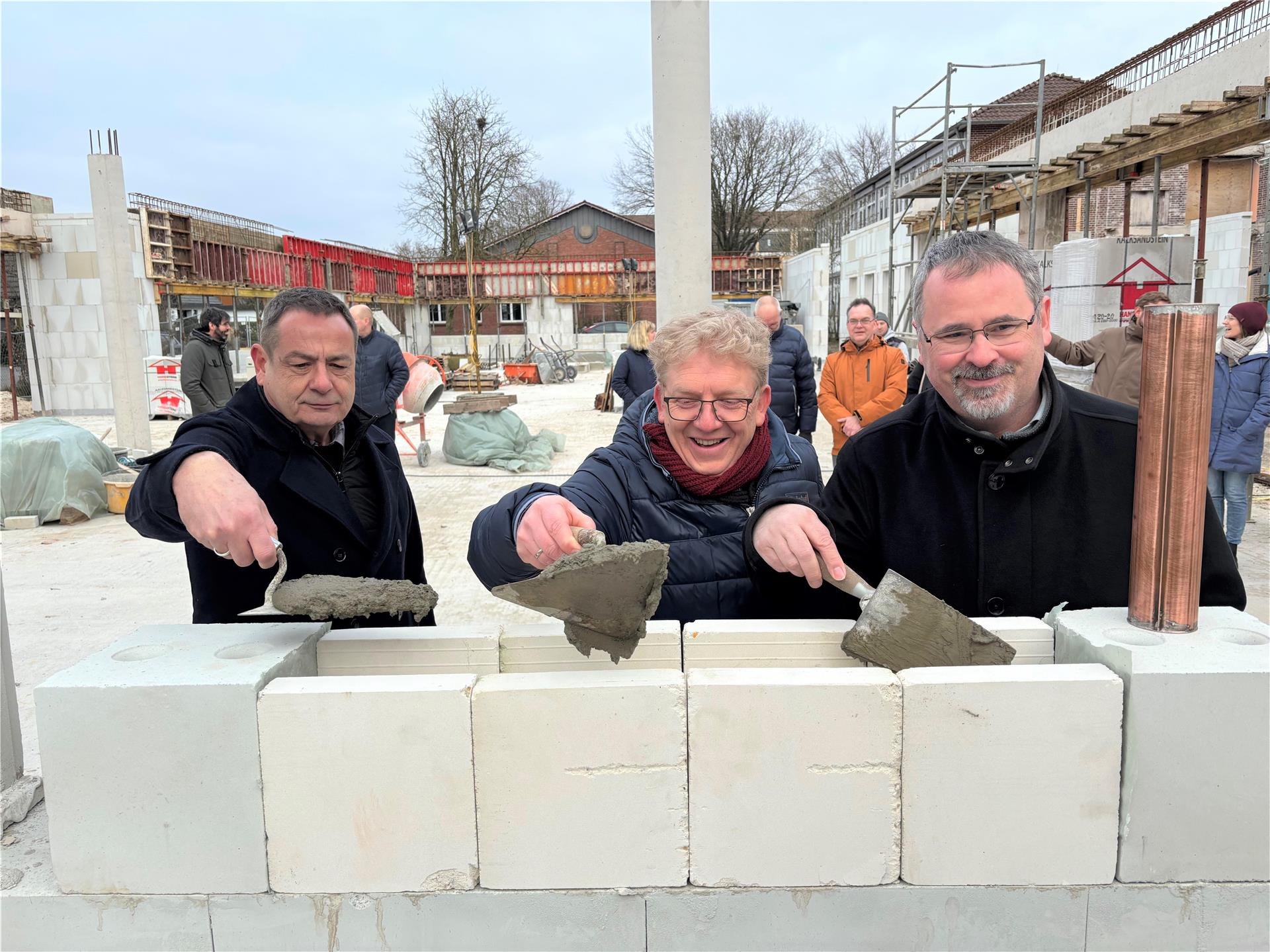 Samtgemeindebürgermeister Oliver Moje, Schulleiter Tim Weidenfeld und Architekt Martin Menzel (von rechts) packen an: Mit einer verspäteten Grundsteinlegung wird das Zukunftsprojekt Mensabau in Tarmstedt gefeiert.