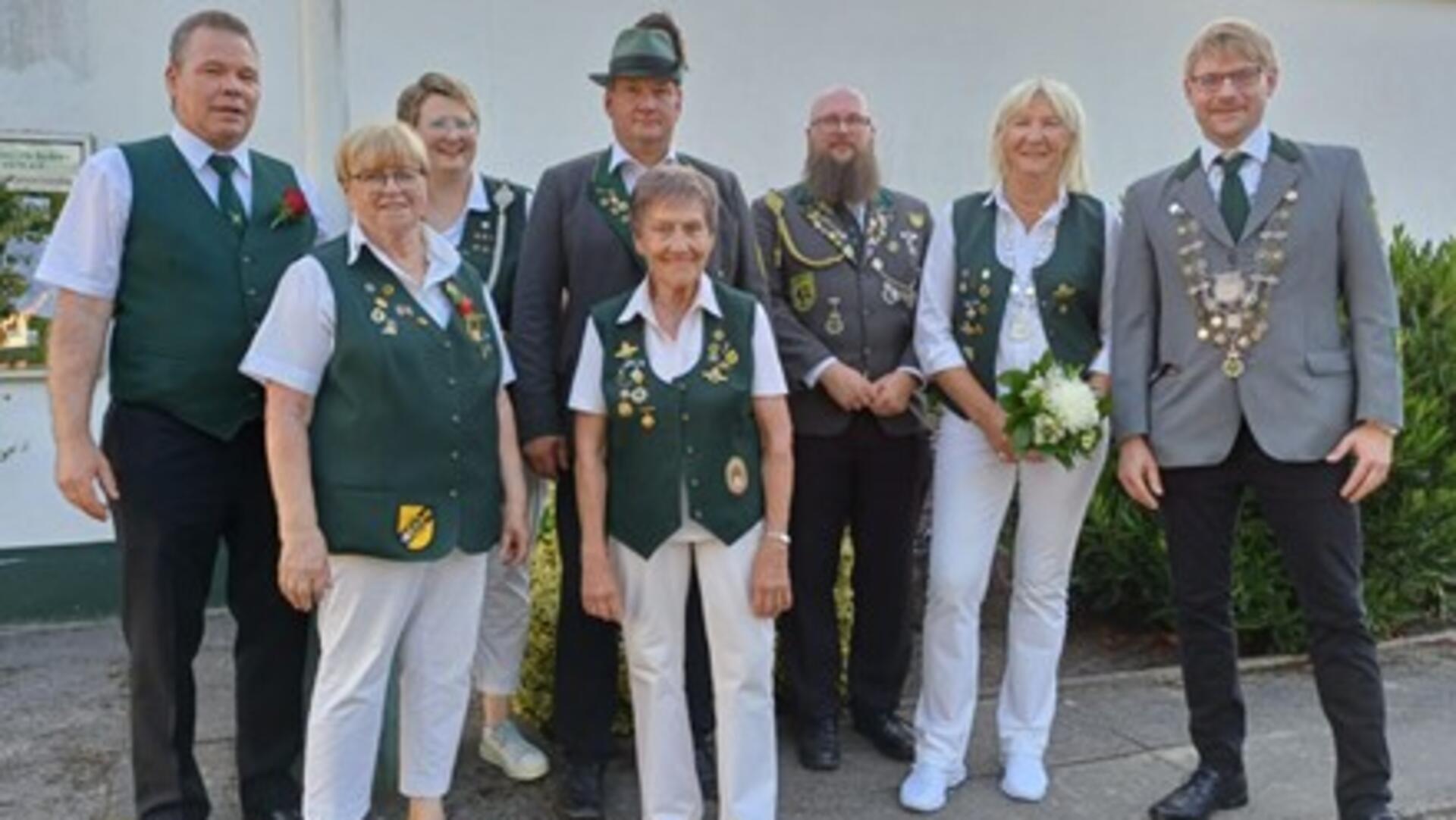 Gruppenfoto mehrerer Mitglieder des Schützenvereins Spaden in traditioneller Vereinskleidung, darunter das neue Königspaar. Einige tragen Schützenketten oder Blumen.