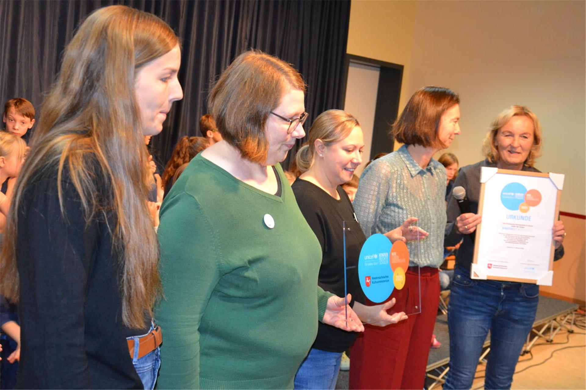 Schulleiterin Heike Gathmann mit der UNICEF-Urkunde und Trainerin Franziska Just sowie die Mitglieder der Steuerungsgruppe, Sandra Houers, Sandra Festin und Sandra Grützmacher (von rechts) mit dem Siegel.