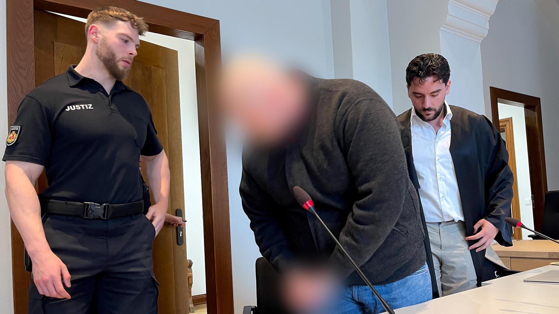 Angeklagter zwischen Justizbeamten und Anwalt.