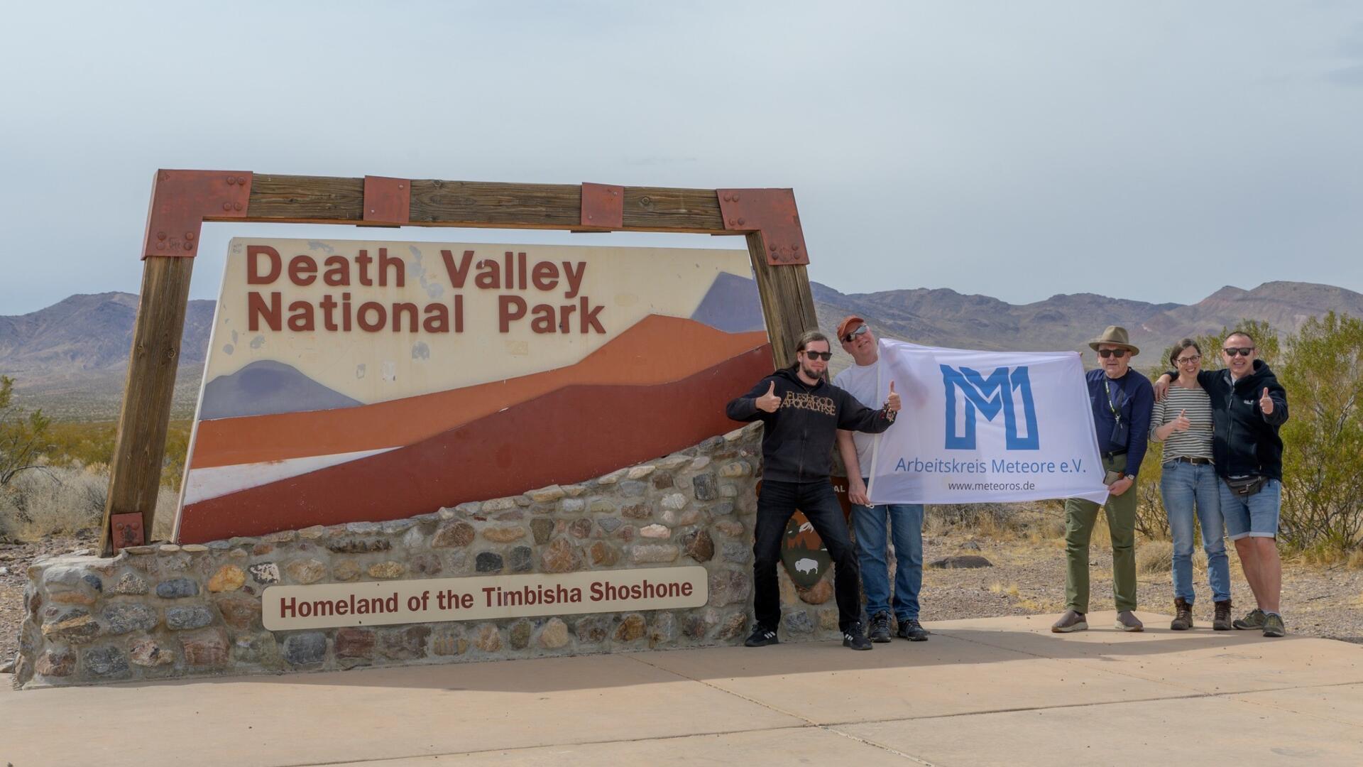Menschen stehen vor einem Schild, auf dem Death Valley National Park steht.