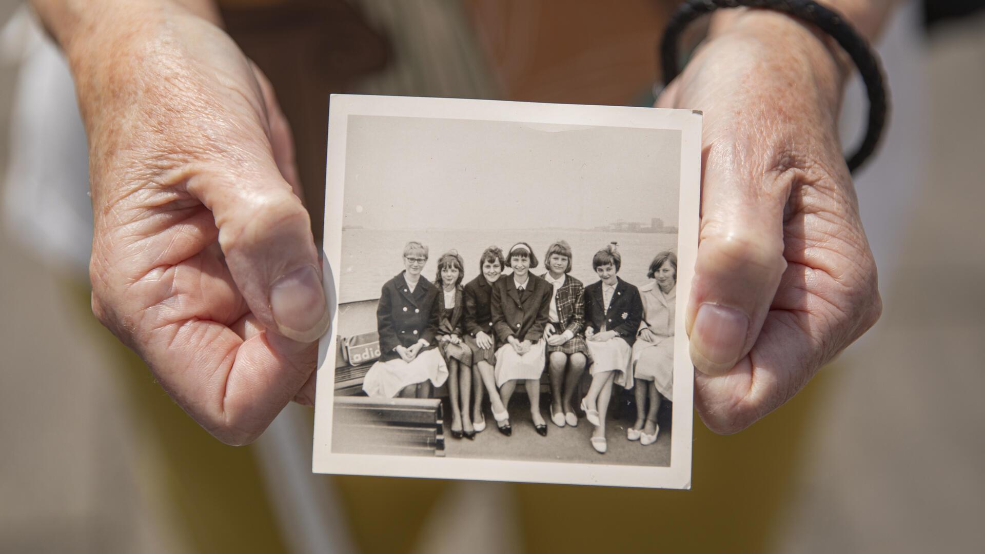 Hände halten ein historisches Bild, das eine Gruppe von Frauen an Deck der Oceana zeigt.