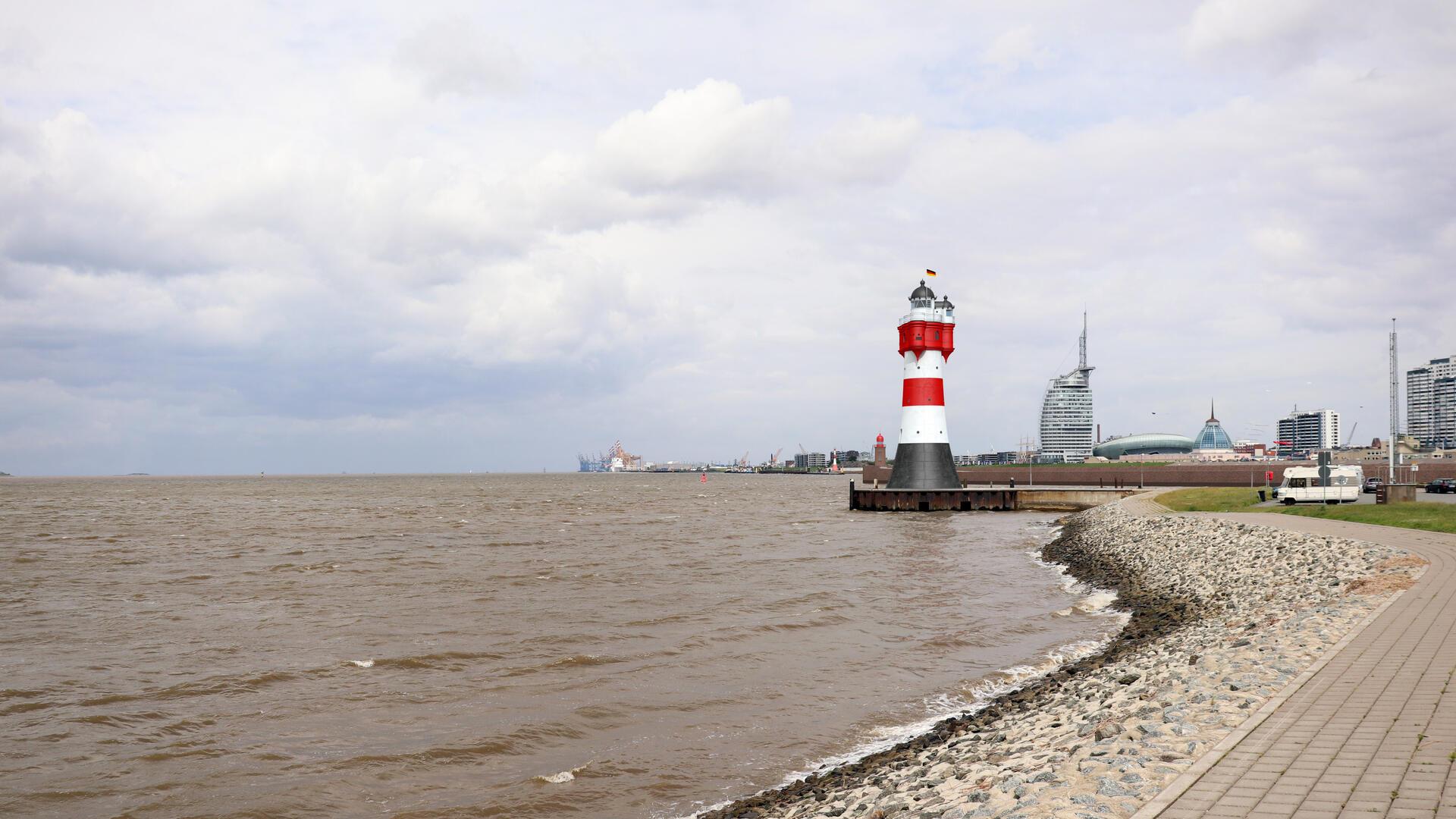 Ein rot-weißer Leuchtturm vor der Skyline Bremerhavens.
