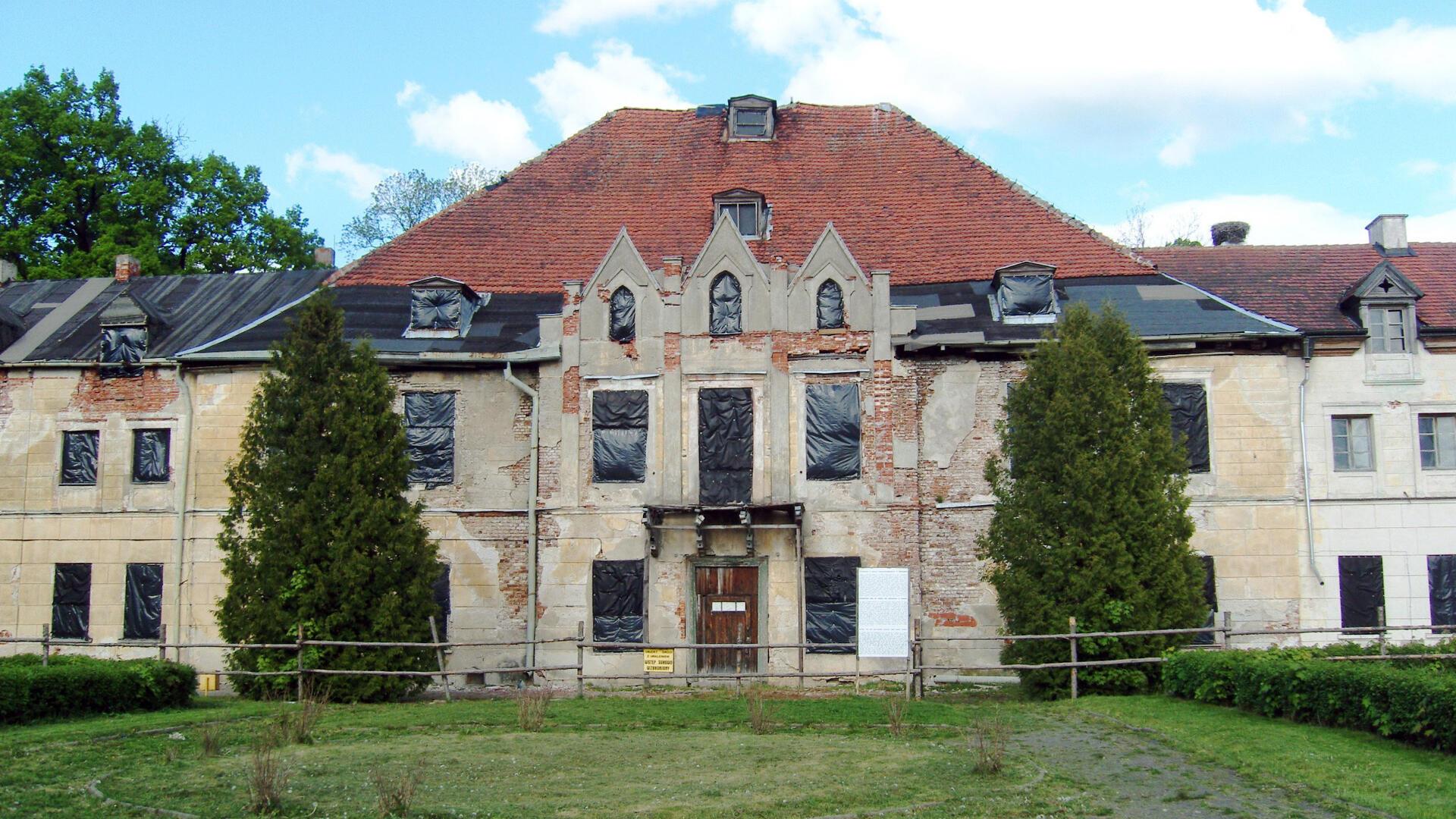 Ein marodes Schloss dessen Fensteröffnungen mit schwarzer Folie verschlossen sind 