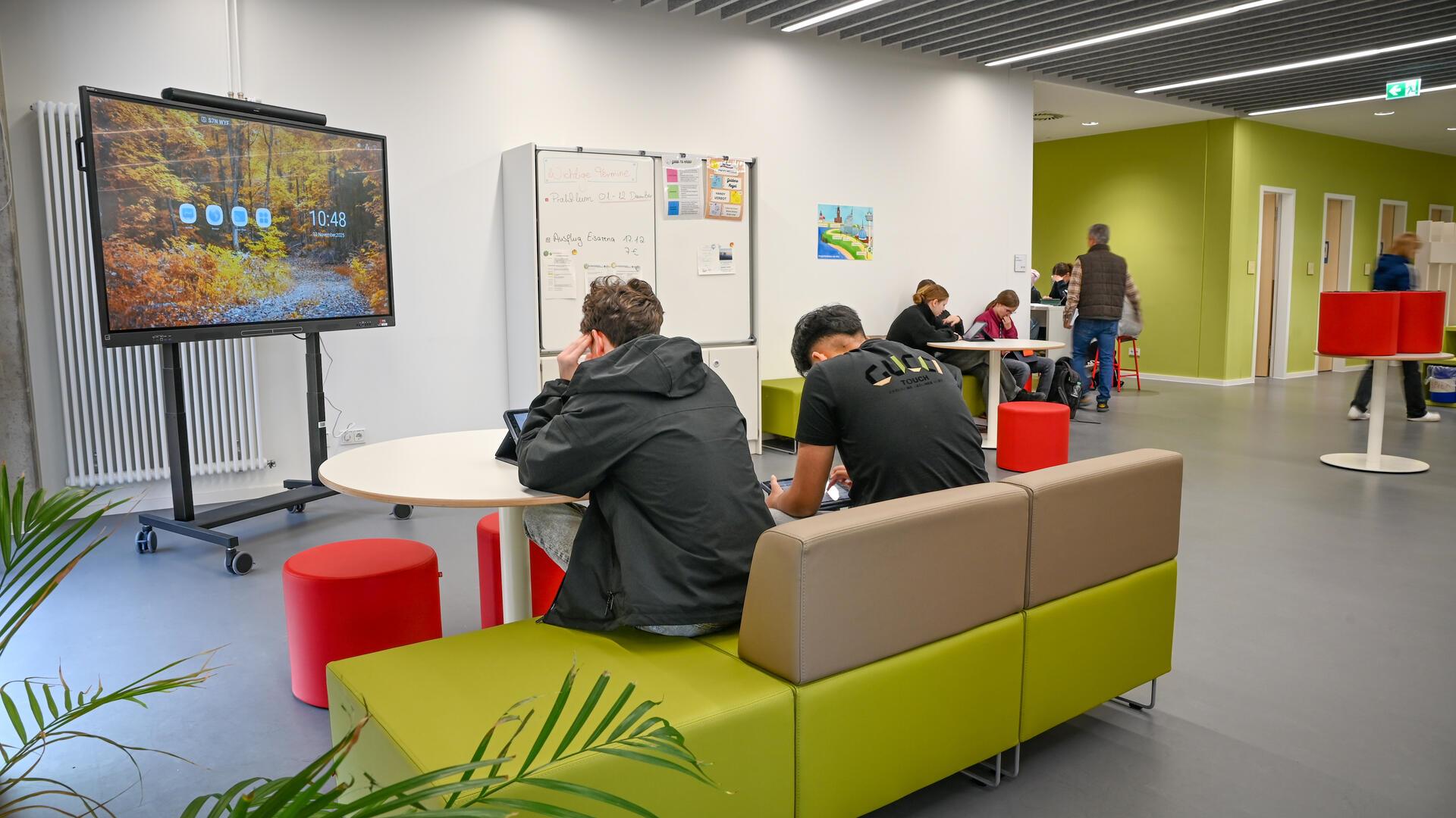 Schülerinnen und Schüler auf einer Couch in einer Schule. 