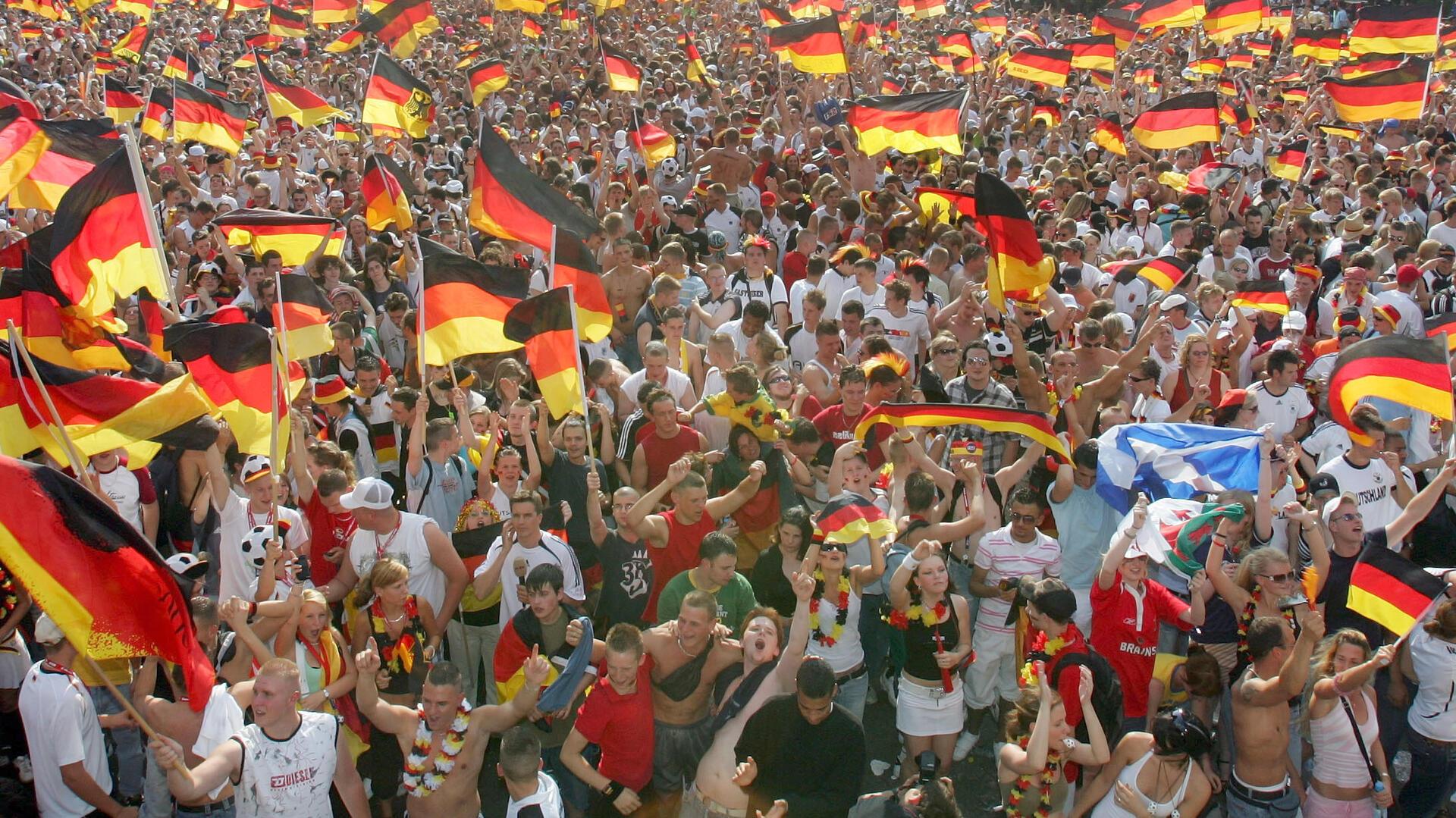 Tausende deutsche Fußballfans schauen zusammen ein Spiel der Nationalmannschaft und schwenken dabei Fahnen