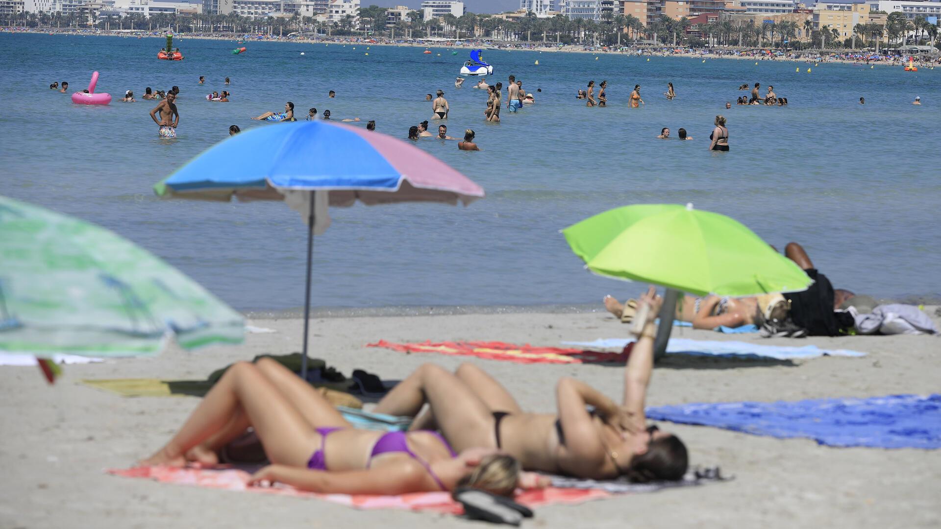 Urlauber liegen unter Sonnenschirmen am Strand