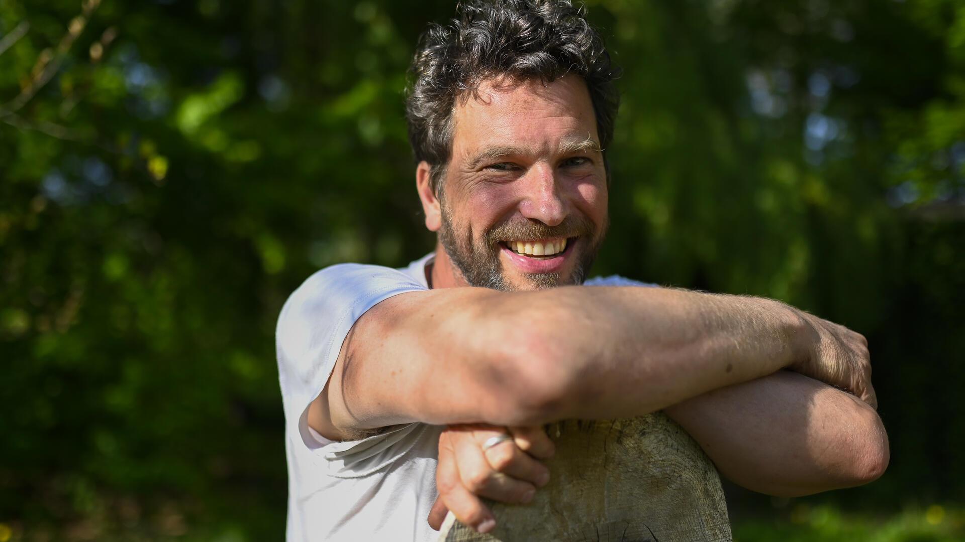 Porträt eines lächelnden Mannes mit dunklen Locken und Vollbart 
