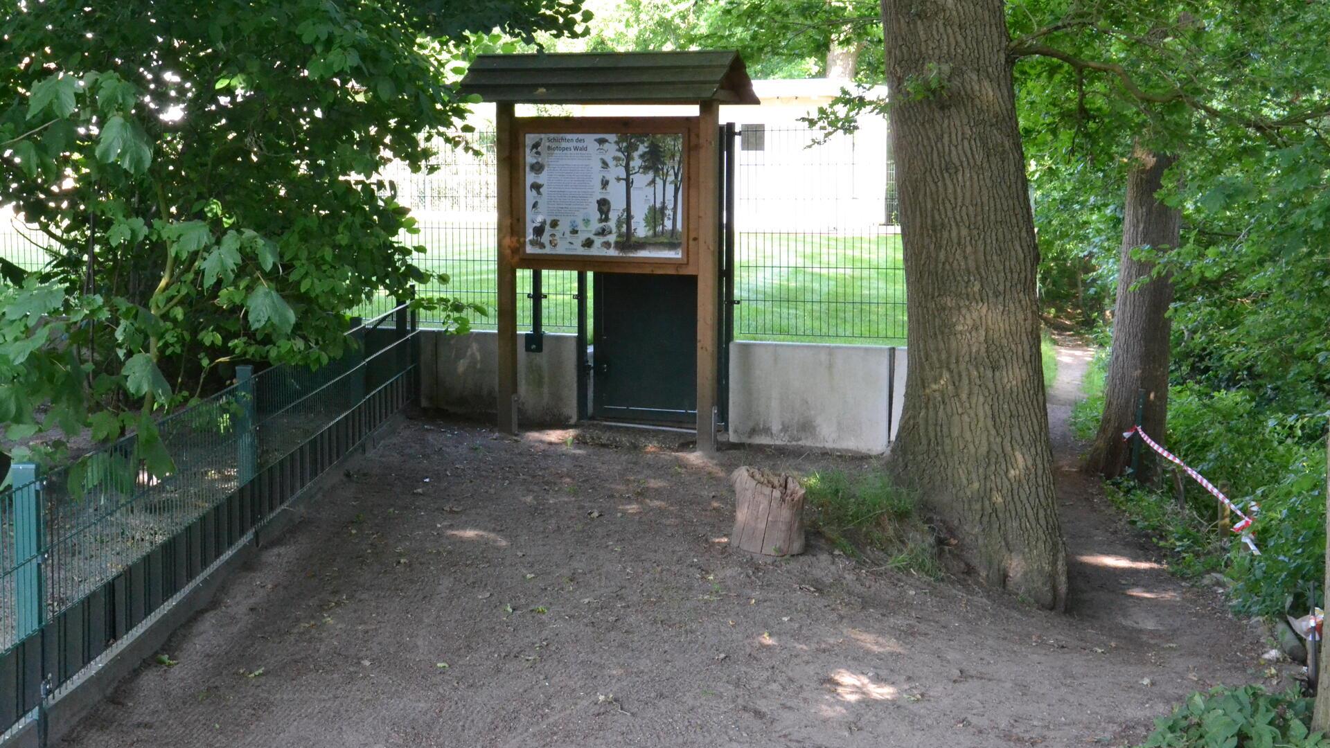 Spaziergänger aus Richtung Offensen biegen vor dem Grundstückszaun und der Schautafel rechts ab auf den Trampelpfad, um den Weg fortsetzen zu können.