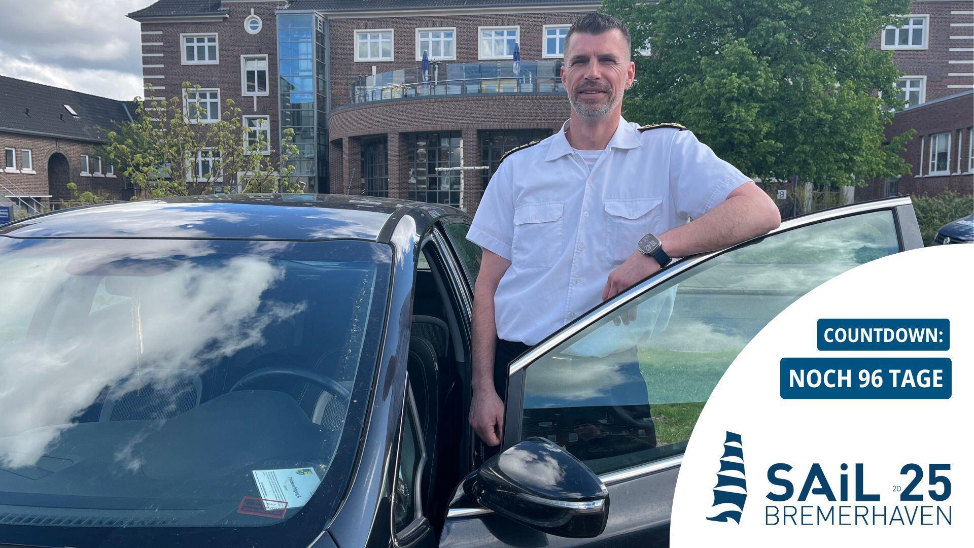 Mann lehnt an einer Autotür: Stabsbootsmann Eik Schomann organisiert den Fahrdienst für Kapitäne, Crew und Ehrengäste während der Sail in Bremerhaven.