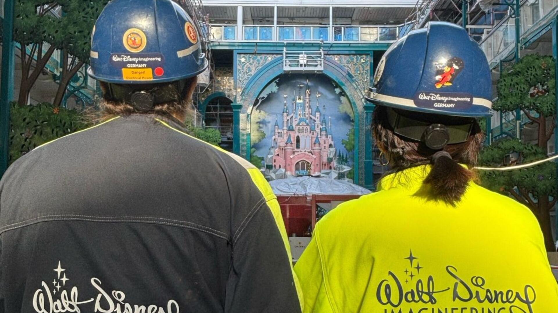 Zwei Menschen von hinten mit Sicherheitshelmen gucken auf ein Schloss an Bord.