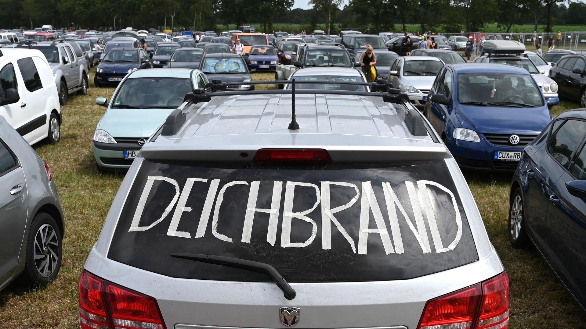 Ein silbernes Auto mit Deichbrand-Schriftzug auf der Heckscheibe steht auf dem Parkplatz neben anderen Fahrzeugen.