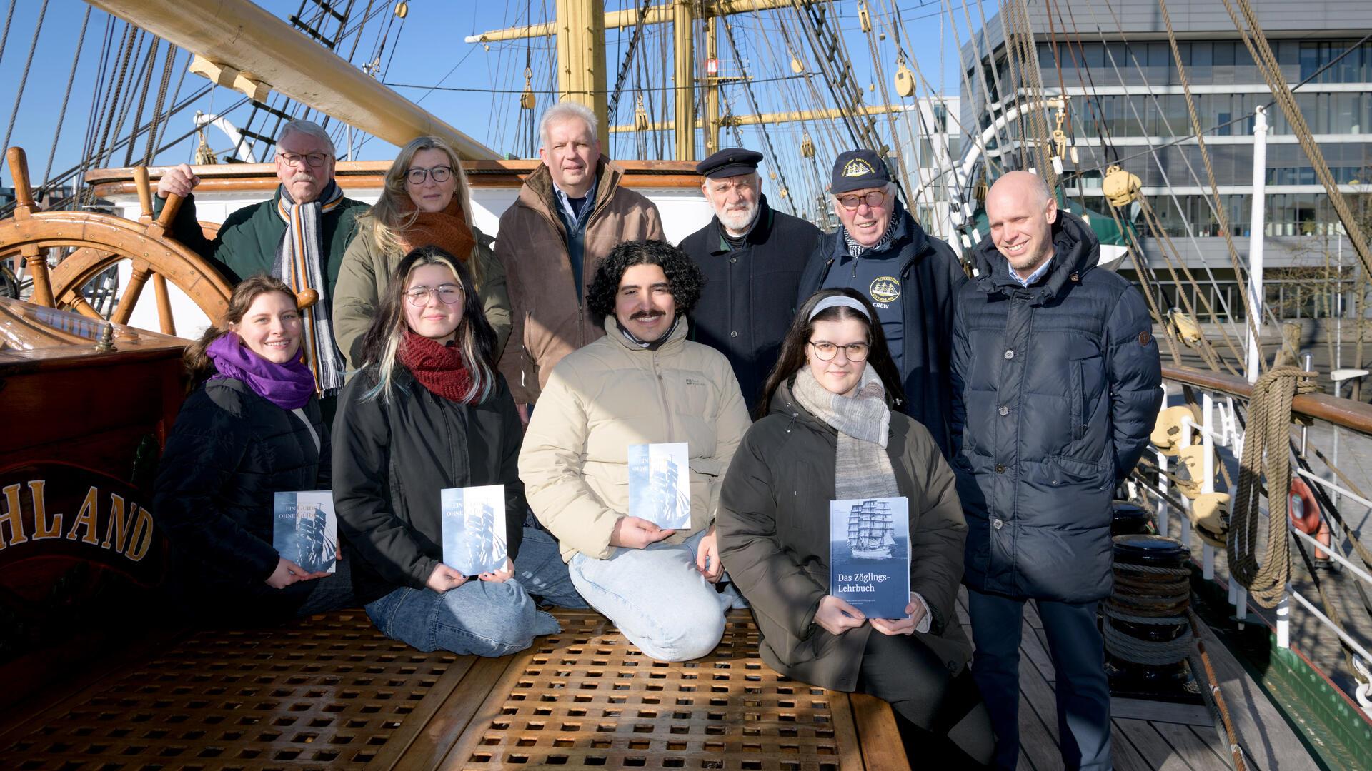 Junge Leute mit Büchern an Deck eines Segelschiffes.