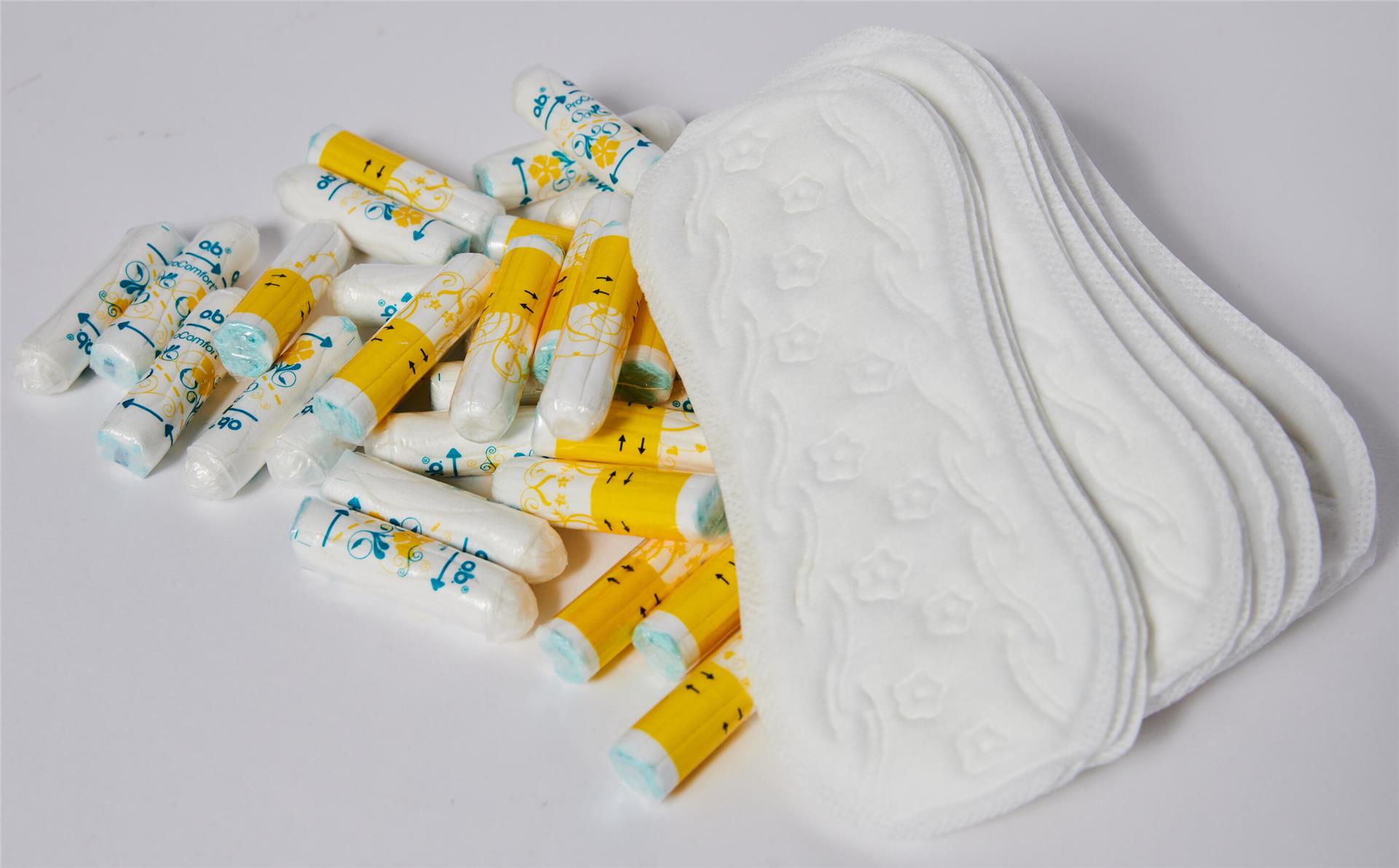 Tampons und Binden verschiedener Marken liegen auf einem Tisch.
