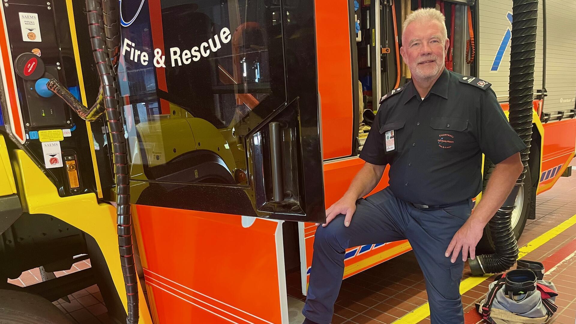 Ein Mann lehnt an einem Feuerwerhrfahrzeug