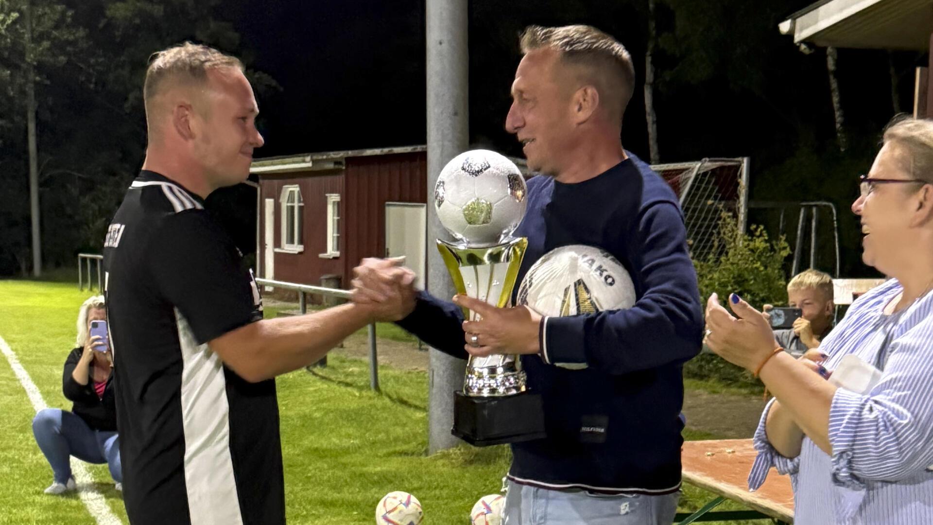 Thorsten Schwarz vom TSV Iselersheim (rechts) überreicht Mannschaftskapitän Christoph Klee vom Siegerteam den Pokal.