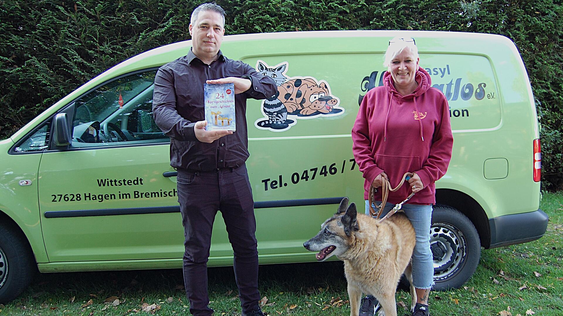 Ein Mann und eine Frau stehen mit einem Hund vor einem Pkw